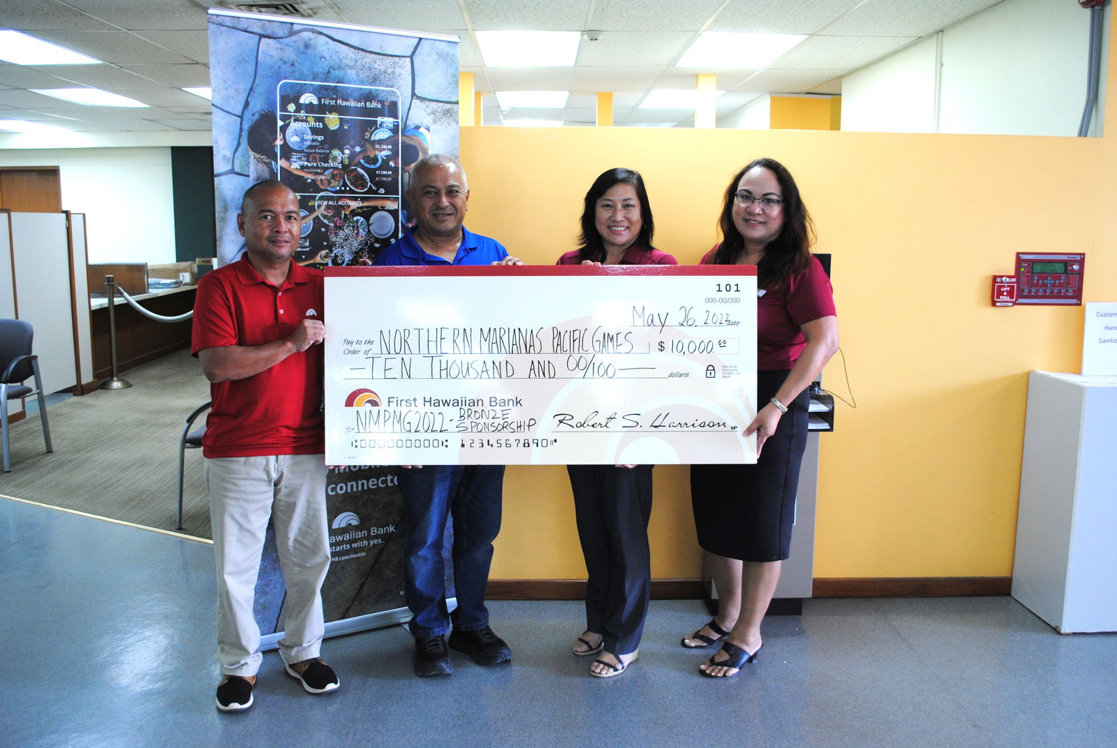 Northern Marianas Pacific Mini Games 2022 CEO Ben Babauta, second left, with First Hawaiian Bank Vice President & Area Manager Vickie Izuka and other bank employees pose for a photo  while holding a check for $10,000 at FHB’s Oleai branch on Thursday.