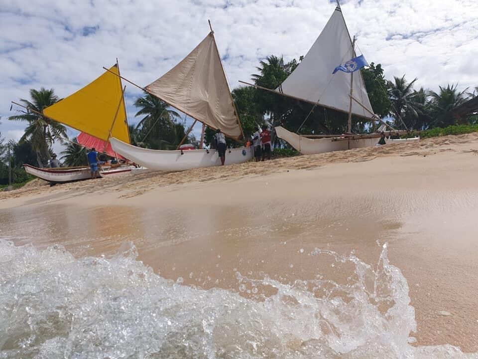 The canoes, from right, Neni (white sail), Anaguan (beige sail), Aunty Oba (yellow sail), and Richard Seman (red sail) are parked under cloudy skies off the shore of Tinian after arrival for the October 2021 Taga Festival.