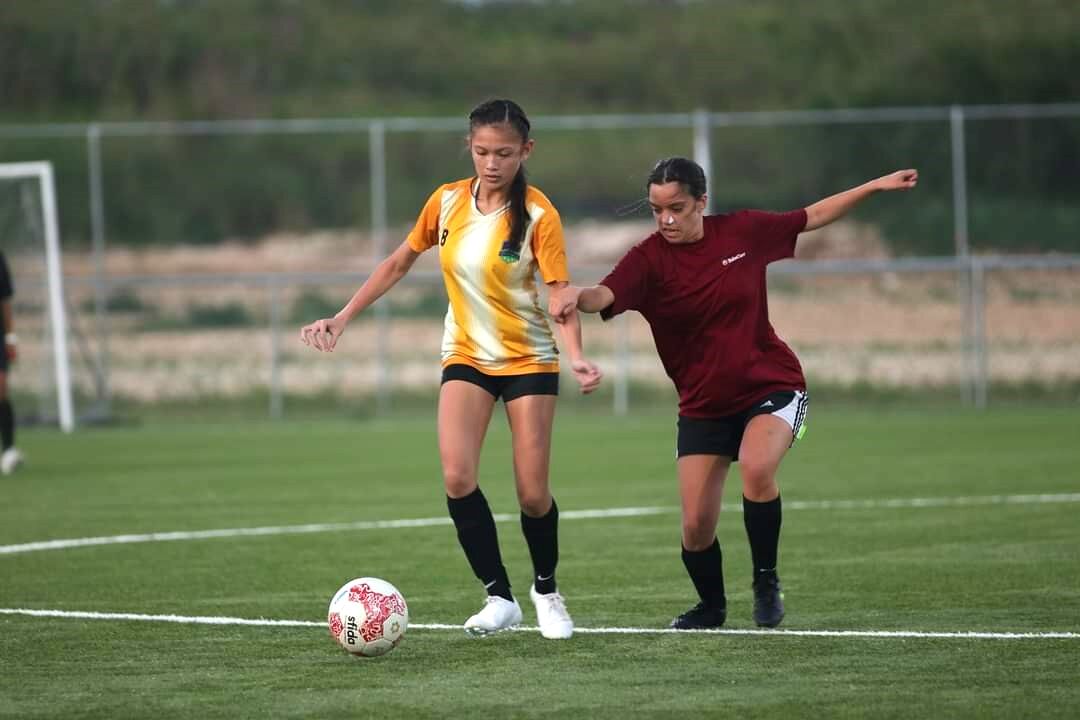 Kanoa's Khristelle Itaas and a TakeCare player race after the loose ball during a premier division game of the Dove Women's League on Wednesday at the NMI Soccer Training Center.