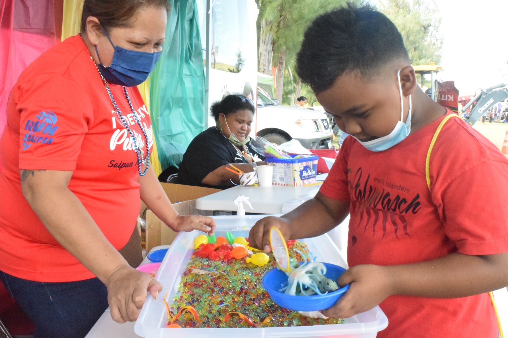Vontae John Borja, 7, scoops toys from a basin of jelly spheres while Joten-Kiyu Public Library Bookmobile Supervisor Leora Terlaje watches during the Division of Youth Services' Family Fun Day at the Minatchom Atdao Pavilion on Saturday.
