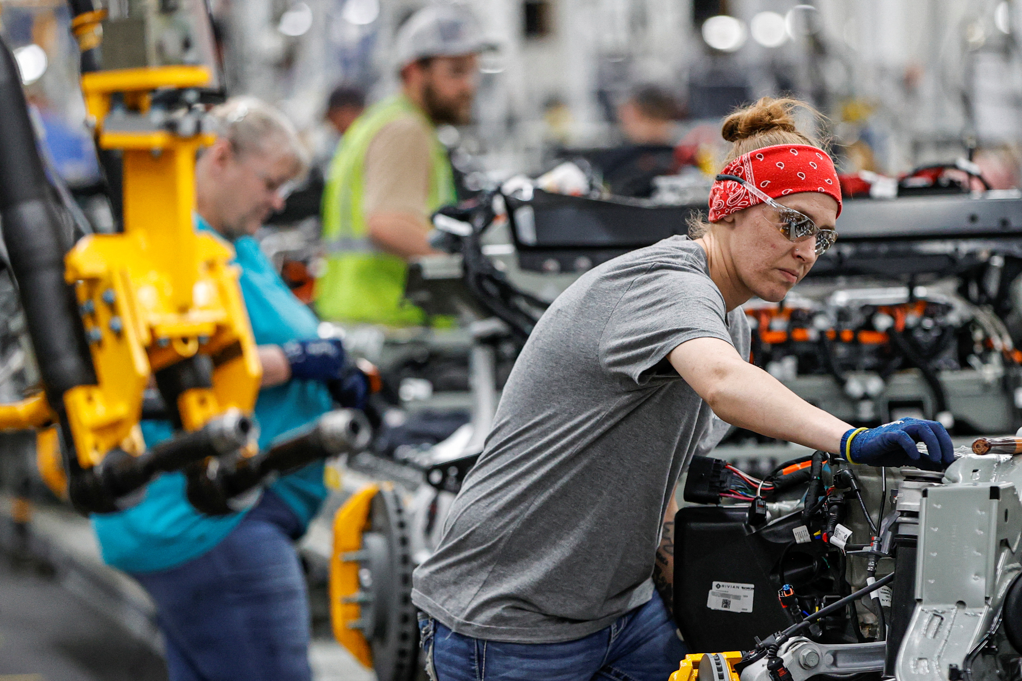 An employee works on an assembly line at startup Rivian Automotive's electric vehicle factory in Normal, Illinois on April 11, 2022.