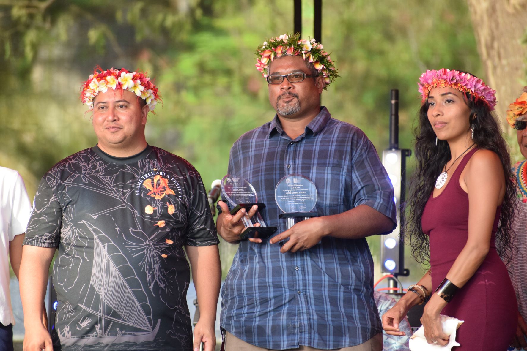 Gov. Ralph DLG Torres poses for a photo with family member of local artists Felix and Lama Lyn Fitial who received posthumous awards during the opening ceremony of the Flame Tree Arts Festival at Sugar King Park on Friday, April 29, 2022. Also in photo is mistress of ceremonies Eva Cruz.