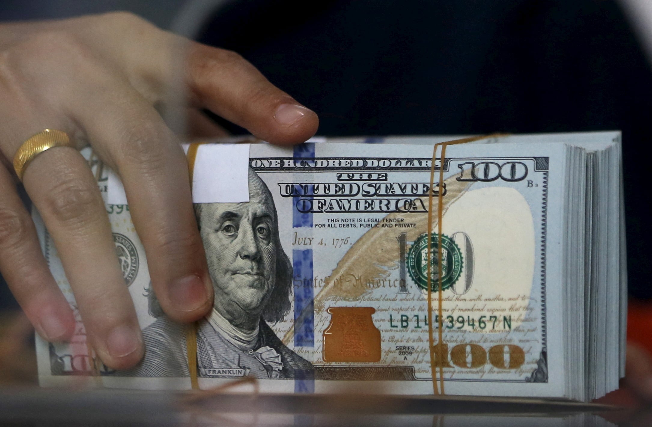 An employee of a money changer holds a stack of U.S. dollar notes before giving it to a customer in Jakarta, Indonesia, Oct. 8, 2015.