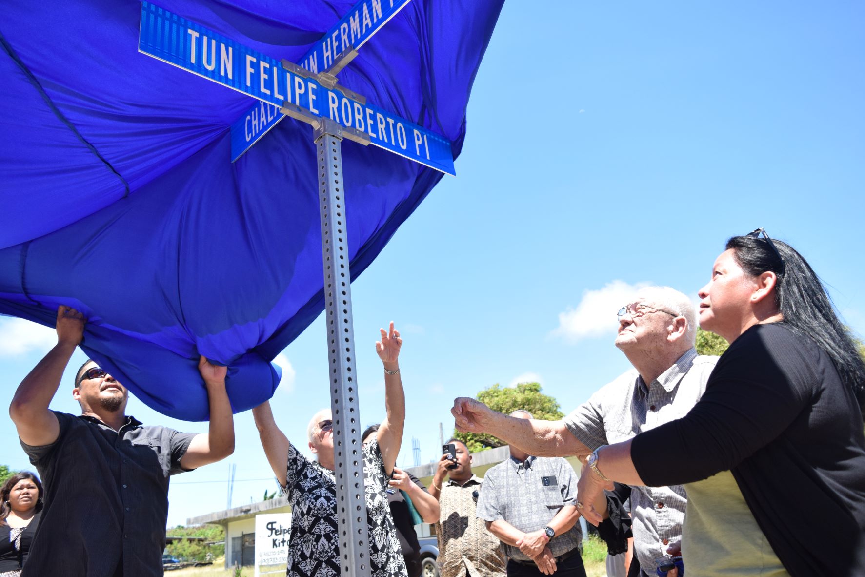 Felipe Ada Roberto is assisted by family members as he unveils a new street name in his honor in Dandan on Tuesday.