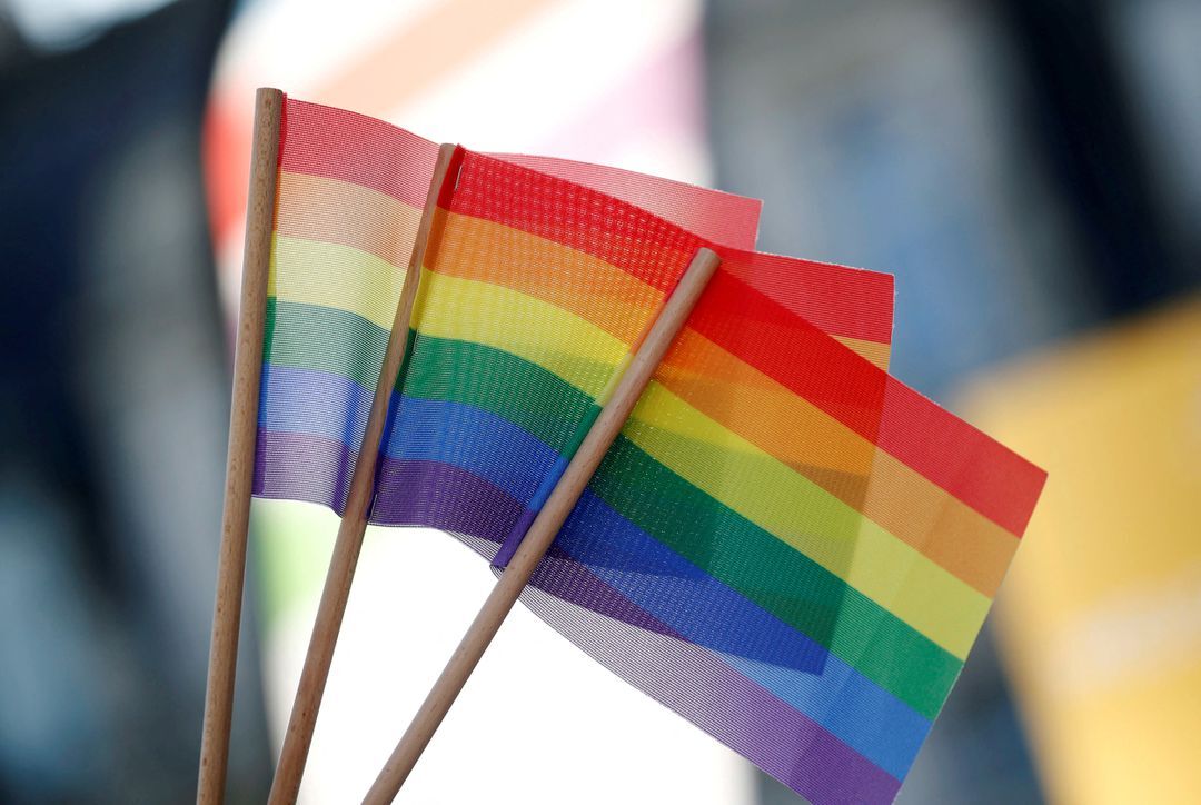 A participant holds rainbow flags at the international Rainbow Memorial Run during the inauguration of the Gay Games village at the Hotel de Ville city hall in Paris, France, Aug. 4, 2018.