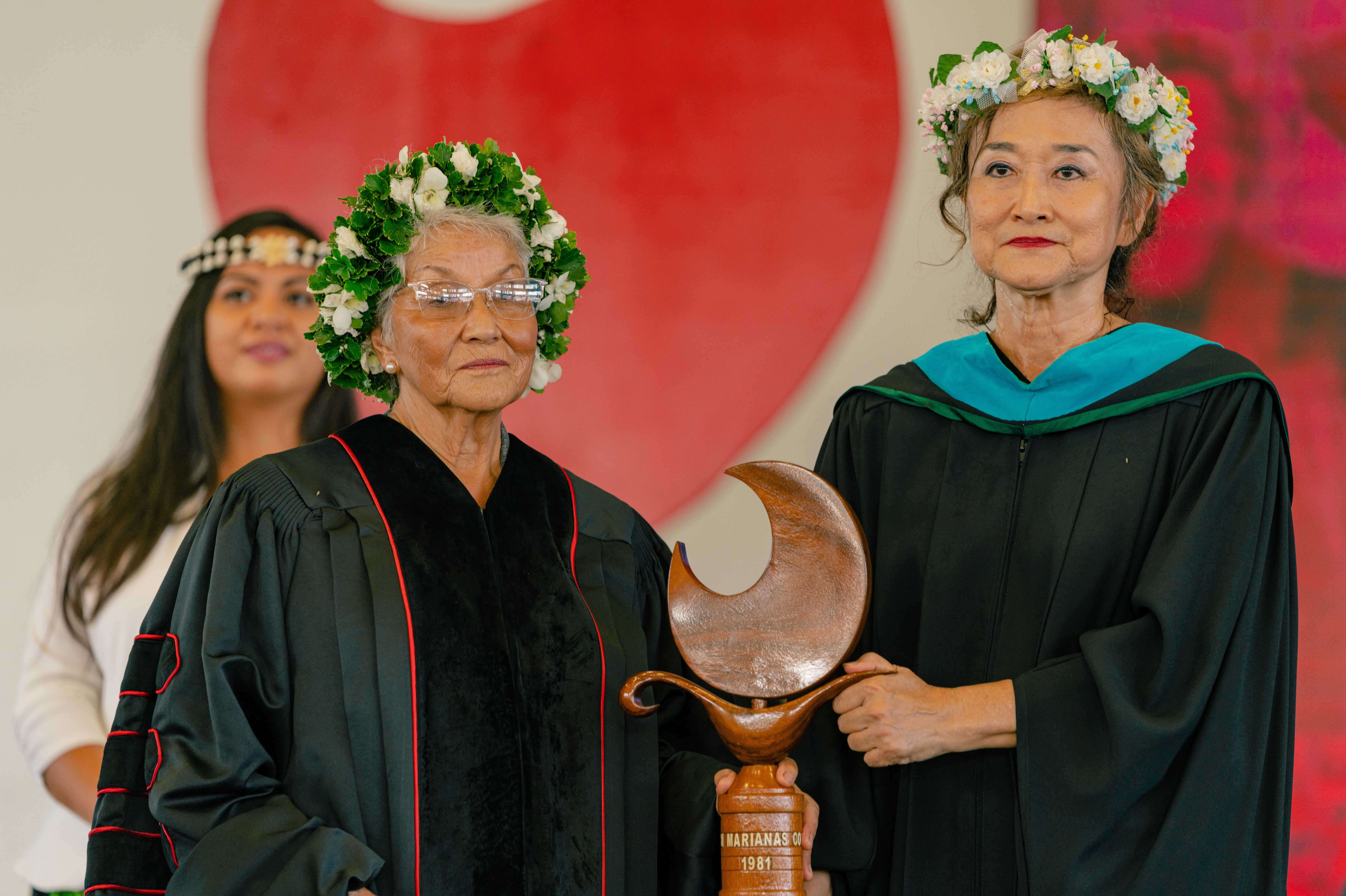 Northern Marianas College Marshal Poonsri “Lek” Algaier, right, and NMC President Emerita Agnes McPhetres hold the college mace.