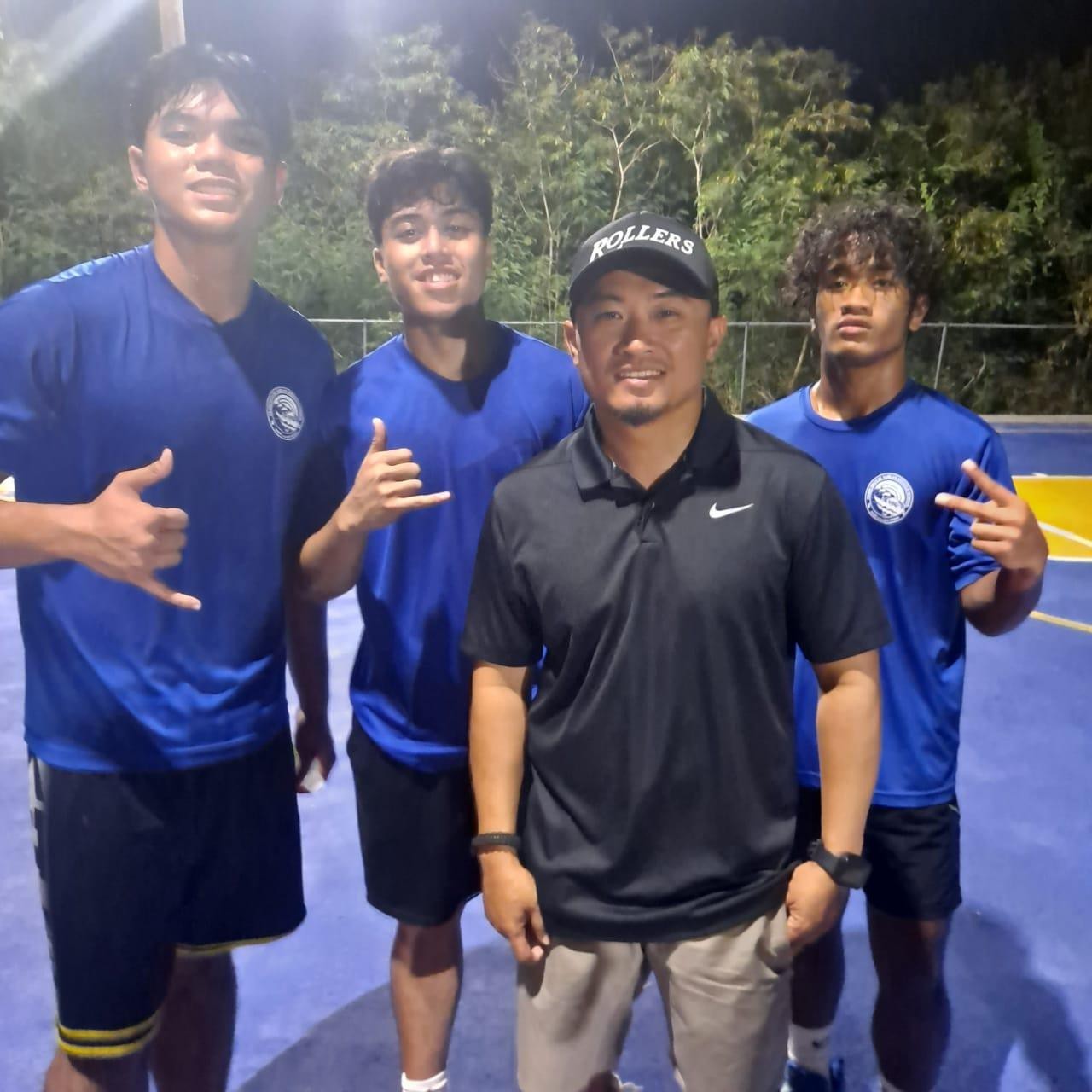 Team Irish Spring’s Emanuel Féria, Elijah Garcia and Gino Asauo stand behind their coach, Mike Mercado, at the Precinct 5 Hoops and Vibes Basketball Tournament in Kagman.