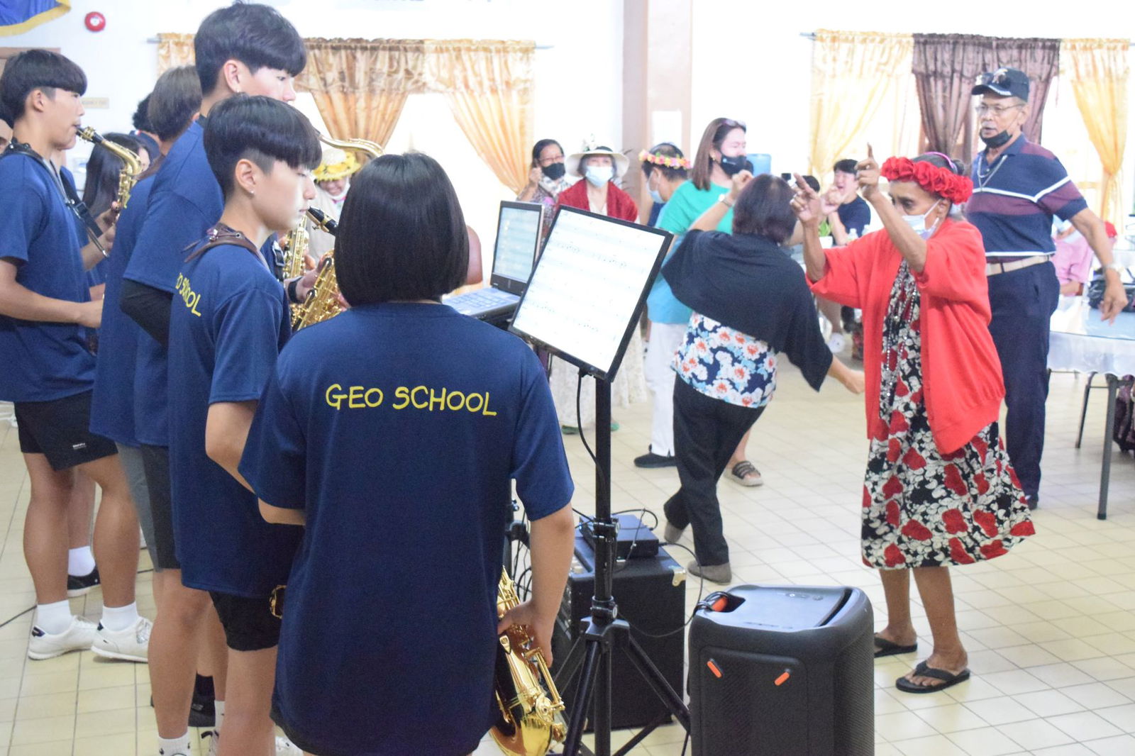Senior citizens dance  during the mini-concert of the Global Education Oriented School saxophone ensemble at the  Manamko' Center on Friday.