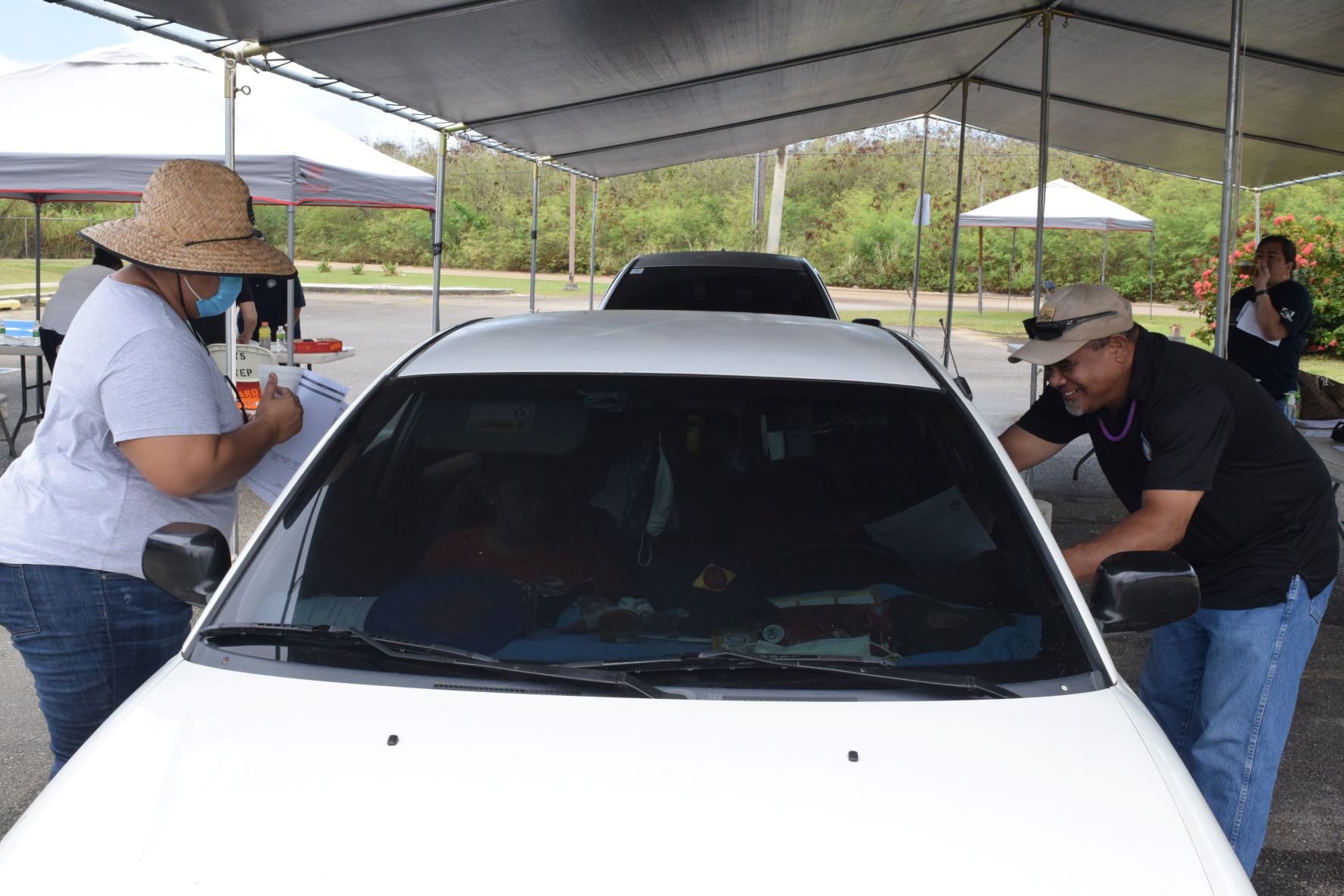 Division of Youth Services' Josephine Kapileo and Alex Olopai speak to a recipient of pandemic emergency assistance at the Kagman Community Center on Friday.