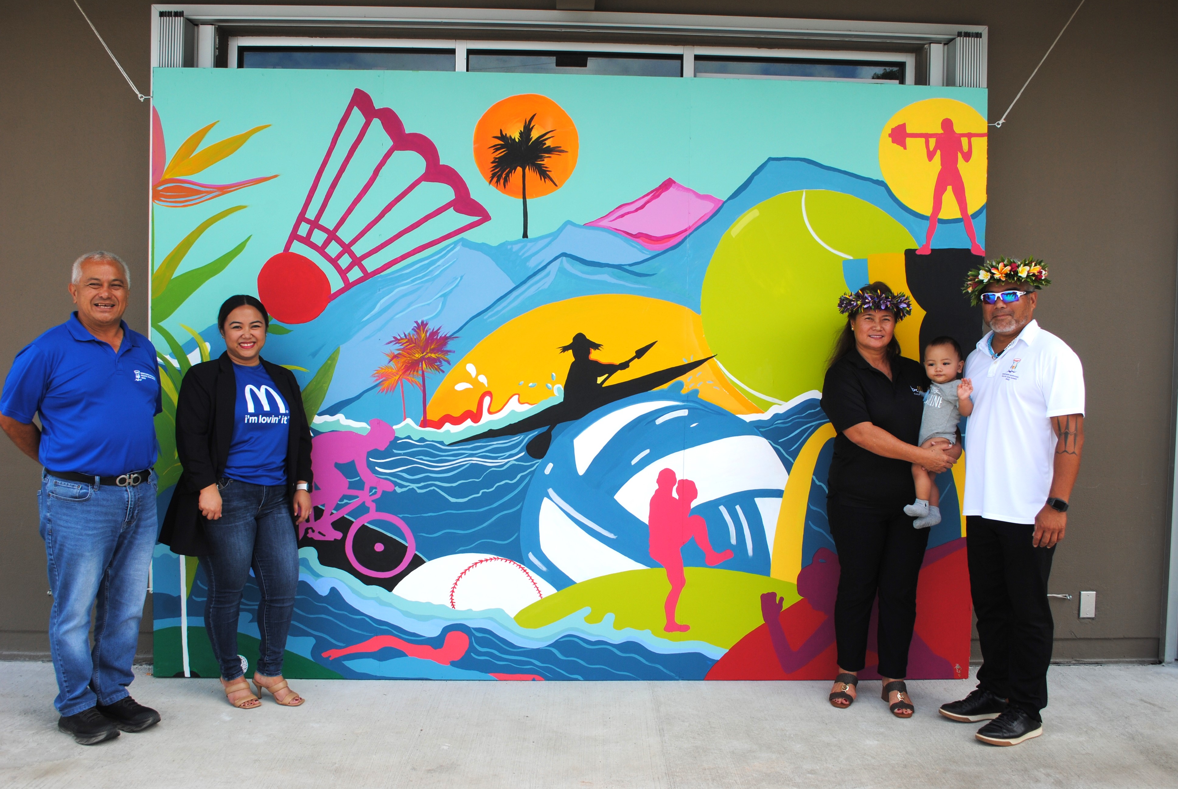 Northern Marianas Pacific Mini Games 2022 CEO Ben Babauta, left, and Chairman Marco Peter, right, pose for a photo with McDonald's of Guam and Saipan Executive Assistant to the President Mable Ayuyu Glenn and Vice President Marcia Ayuyu at McDonald’s Middle Road. In the background is a mural that celebrates the 2022 Pacific Mini Games.