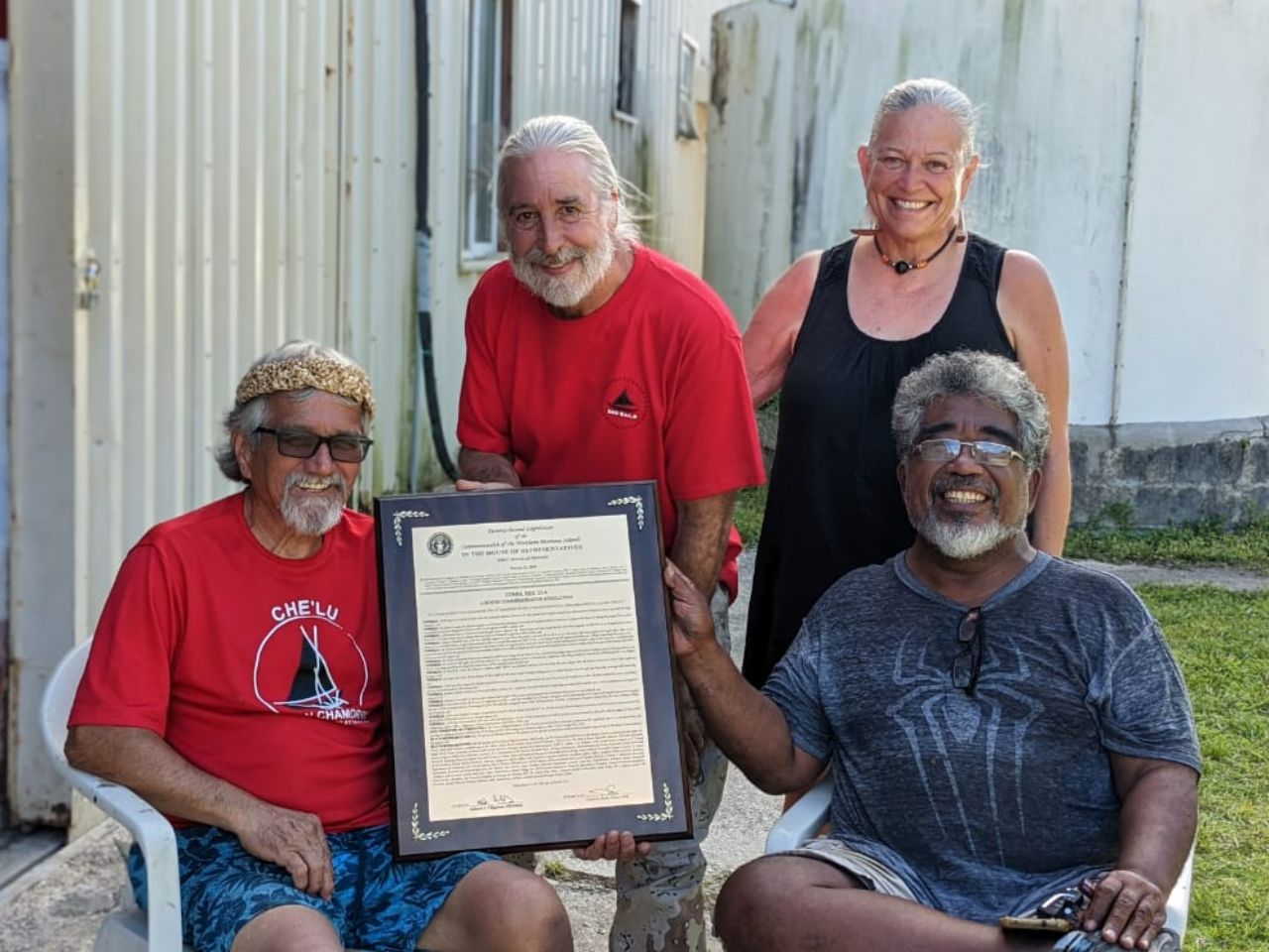 500 Sails co-founders Peter, back left, and Emma Perez, back right, and Master Navigator Mario Benito, front right, present Chamorro Engineer & Boatbuilder Mario "Sakman" Borja, front left, with the CNMI legislative resolution honoring Che'lu', just outside the 500 Sails Boatyard on May 24, the day before his departure to the mainland.