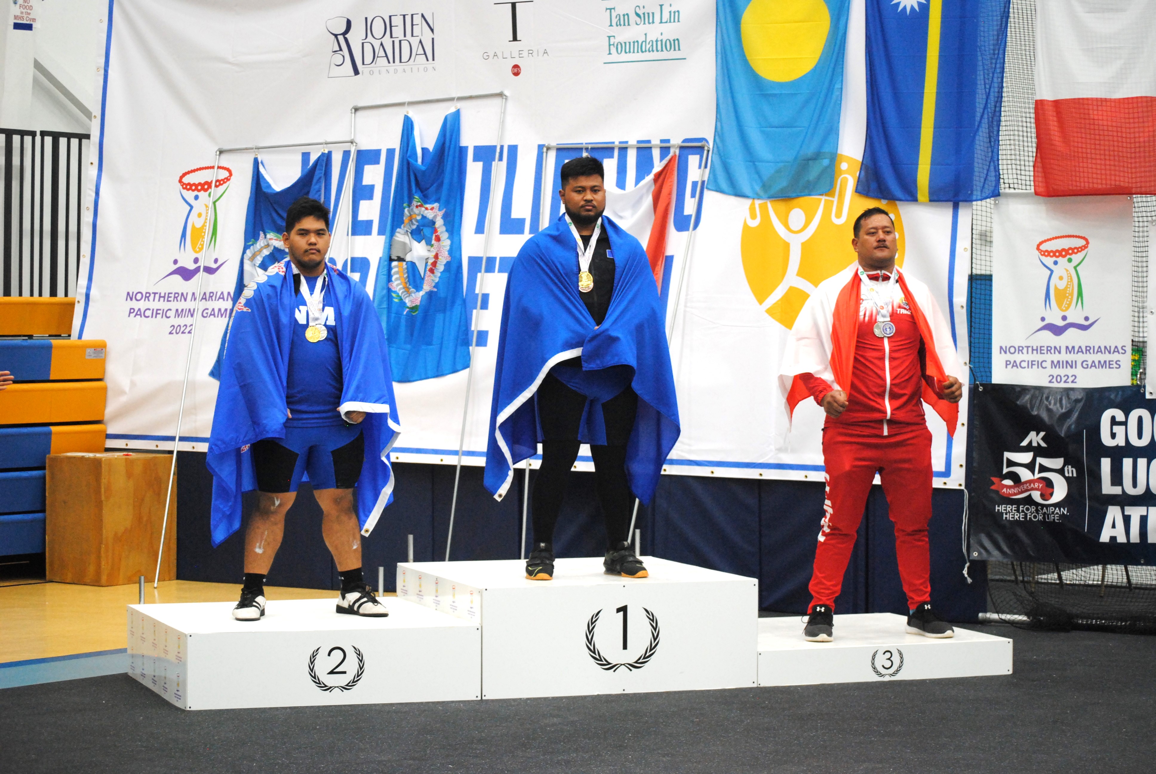 The NMI's Jason Limes, center, and Joey Colisao, left, join Timothy Vakuruivalu of Fiji at the podium during the medal ceremony for the +109kg weight class at the MHS gym.