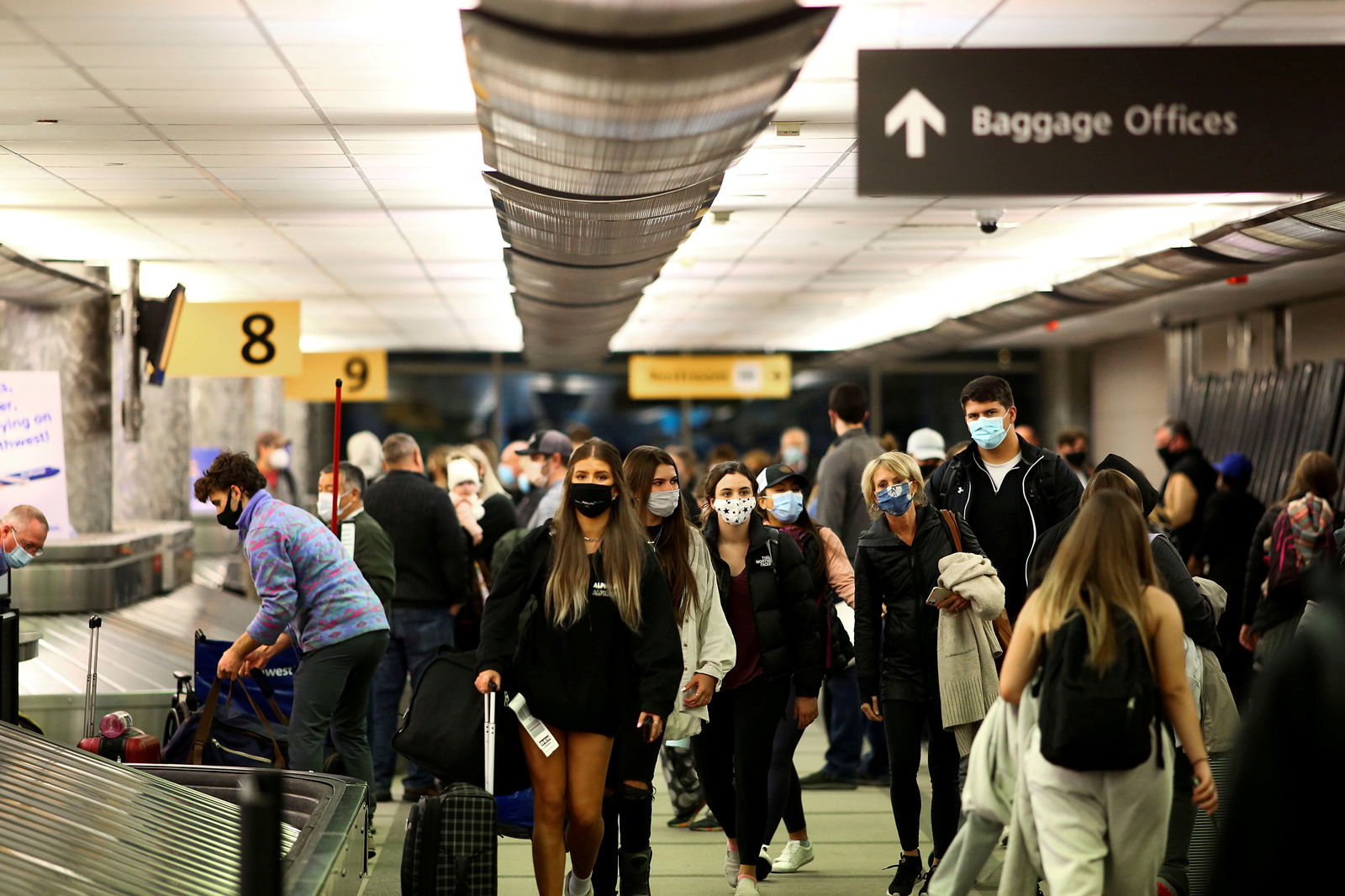 Travelers wearing protective face masks to prevent the spread of the coronavirus disease reclaim their luggage at the airport in Denver, Colorado, Nov. 24, 2020.