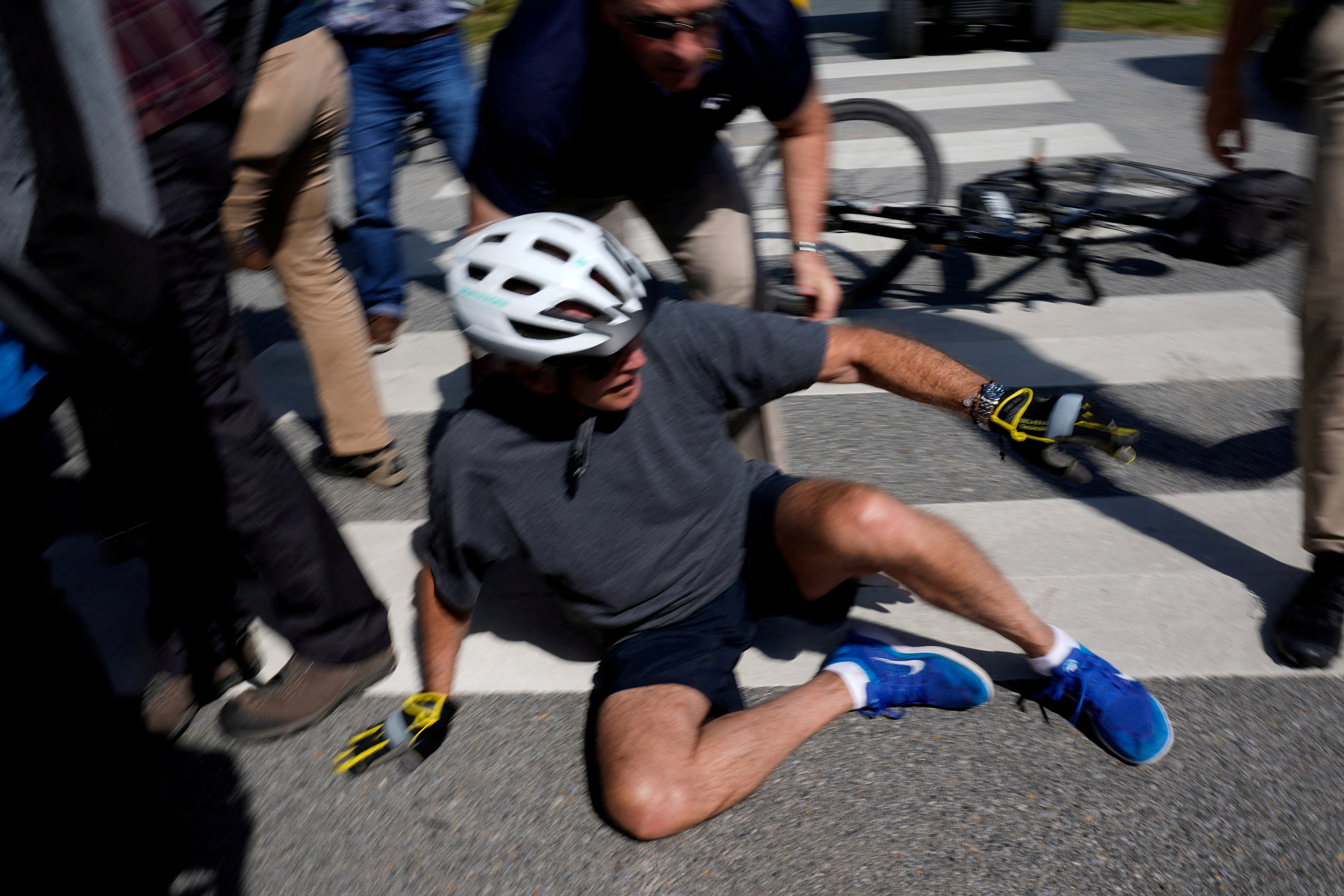 President Joe Biden falls to the ground after riding up to members of the public during a bike ride in Rehoboth Beach, Delaware, June 18, 2022.