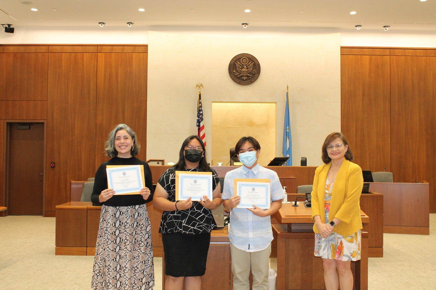 Marianas High School Language Arts teacher Ashley Beck, left, receives the award certificate for her student Jenny Min while posing for a photo with the other civics essay contest winners Samantha Flores and John Lawrence Apit, and Chief Judge Ramona V. Manglona of the District Court for the NMI.