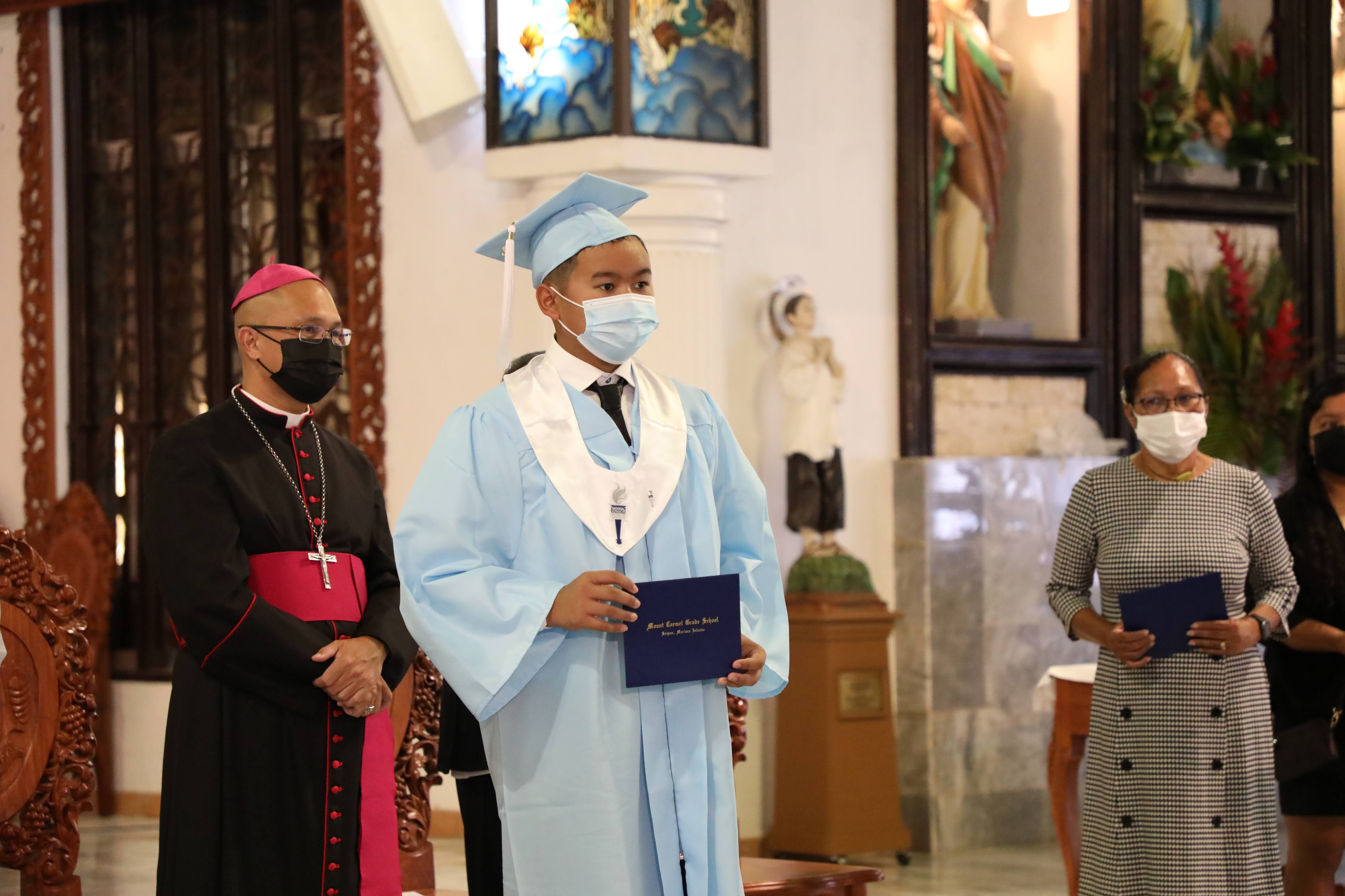 Mount Carmel School student Oscar Bien Reyes Buenaflor receives his diploma during the school’s 8th-grade promotion ceremony on June 4, 2022.