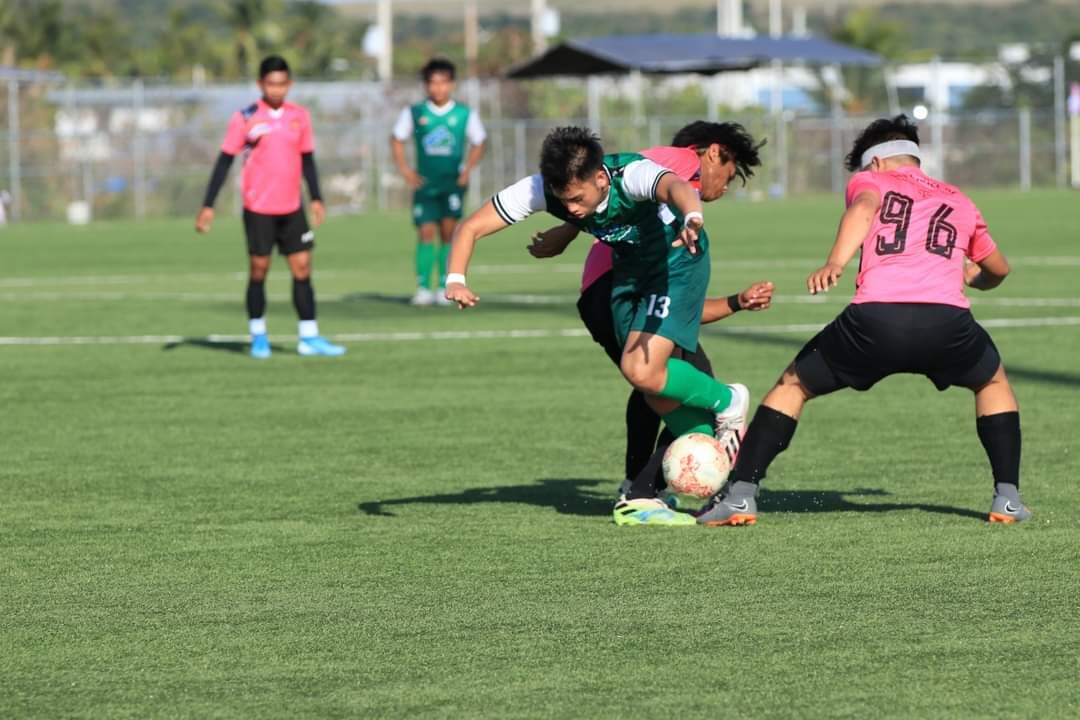 Tan Holdings FC's Joshua Abragan attempts to dribble between two defenders during a Division A game of  the Men's Marianas Soccer League at the NMI Soccer Training Center.