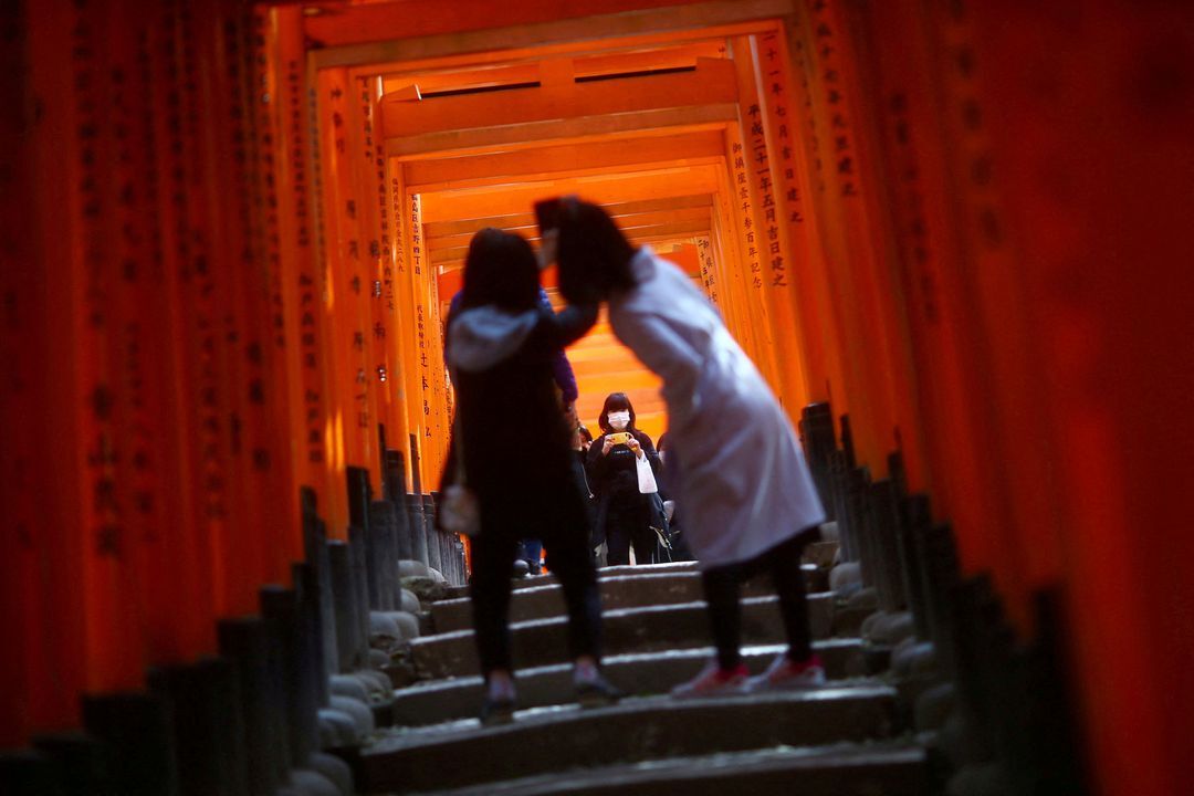 Visitors, wearing masks following the outbreak of the coronavirus disease, explore the wooden torii gates at Fushimi Inari Taisha Shinto shrine in Kyoto, Japan on March 13, 2020.