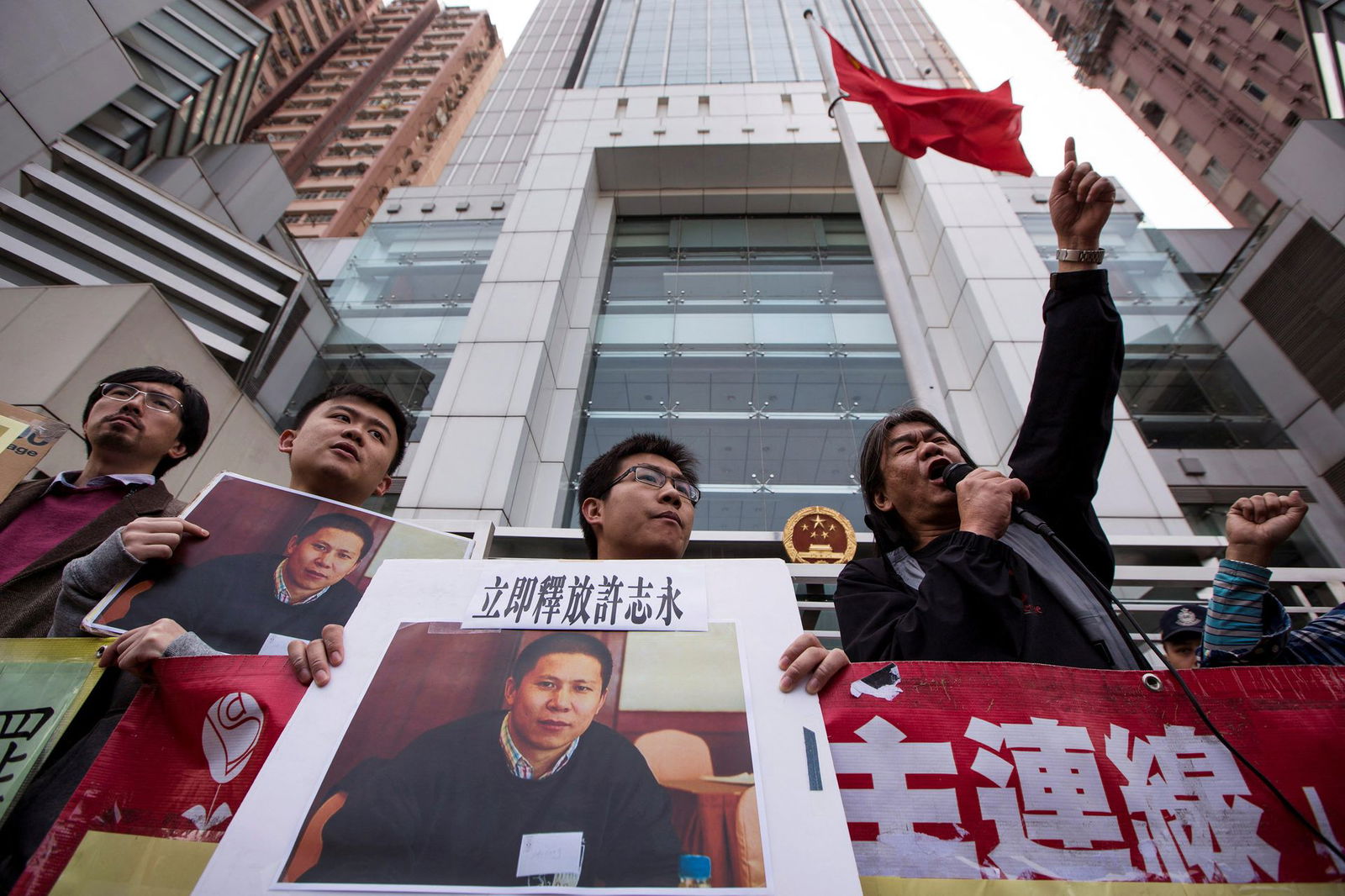 Outside the Chinese liaison office in Hong Kong on Jan, 27, 2014, protesters hold images of Chinese rights advocate Xu Zhiyong during a demonstration calling for his release. Words above a picture of Xu read, "Release Xu Zhiyong immediately."