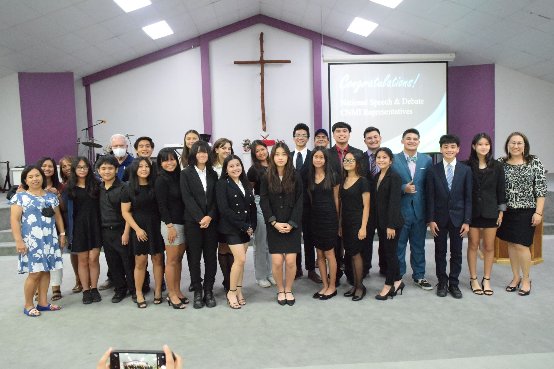 The CNMI representatives to the 2022 National Speech & Debate and International Thespian Festival pose for a photo with their coaches after performing in the Grace Christian Academy auditorium on Tuesday.