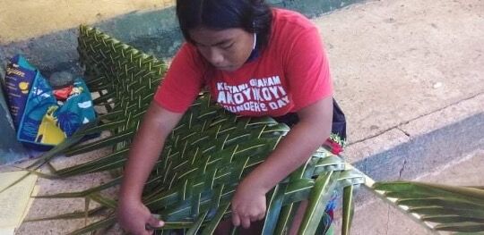 A student at Akoyikoyi School practicing leaf weaving.