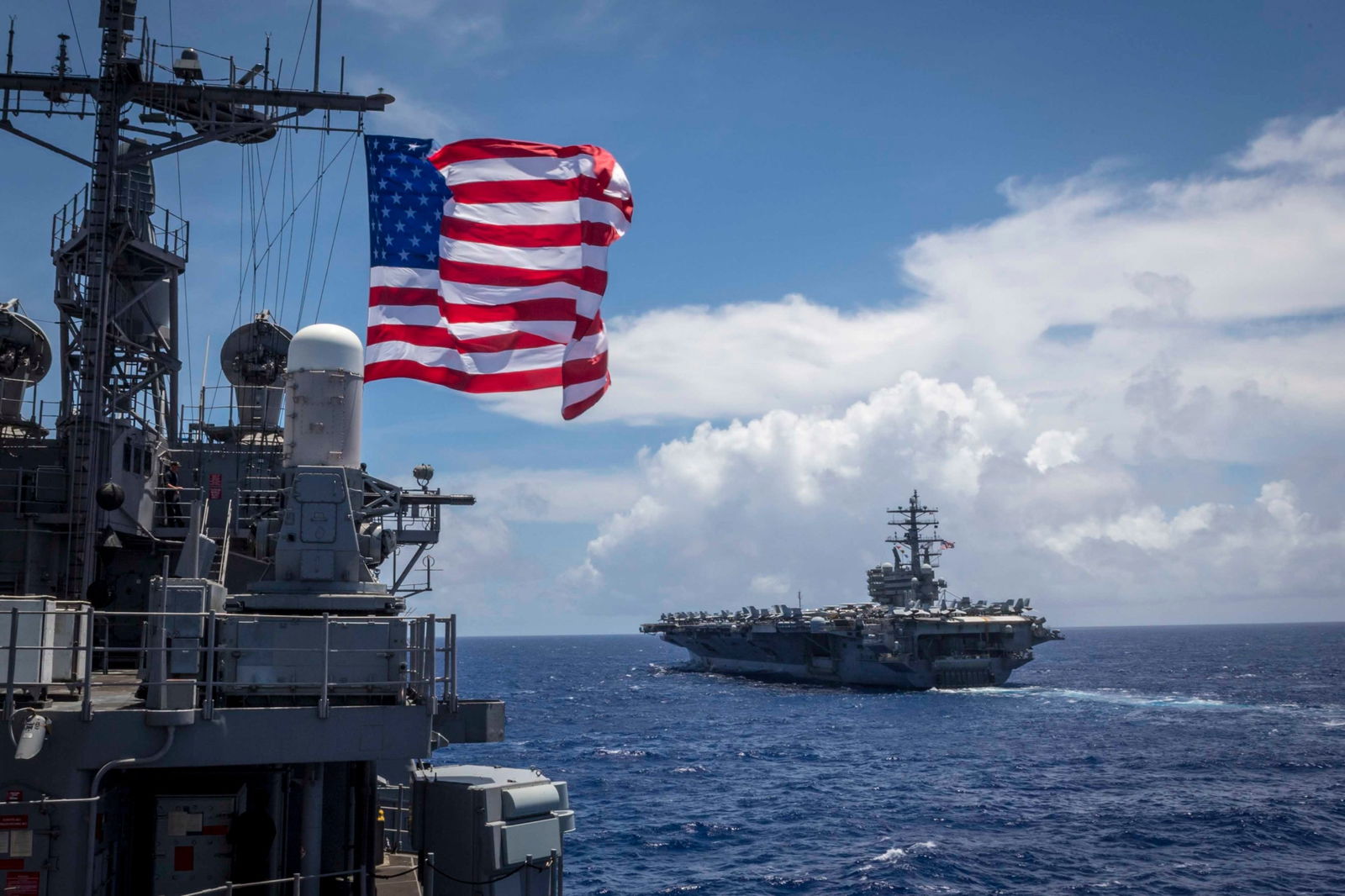 The Ticonderoga-class guided-missile cruiser USS Chancellorsville sails behind the aircraft carrier USS Ronald Reagan  while in formation for a photo exercise during Valiant Shield 2018 on Sept. 17, 2018.