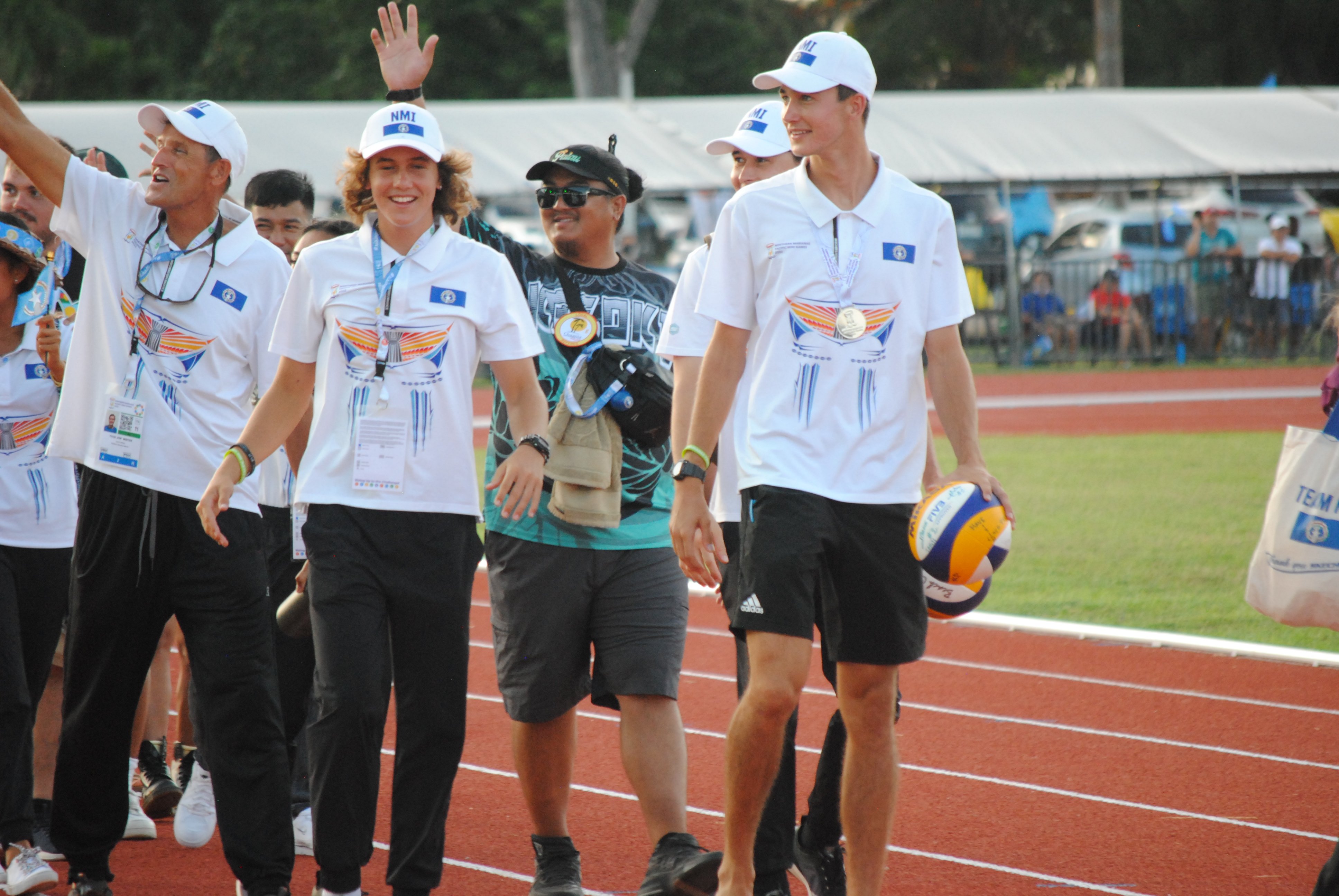 The NMI beach volleyball team members wave at spectators.