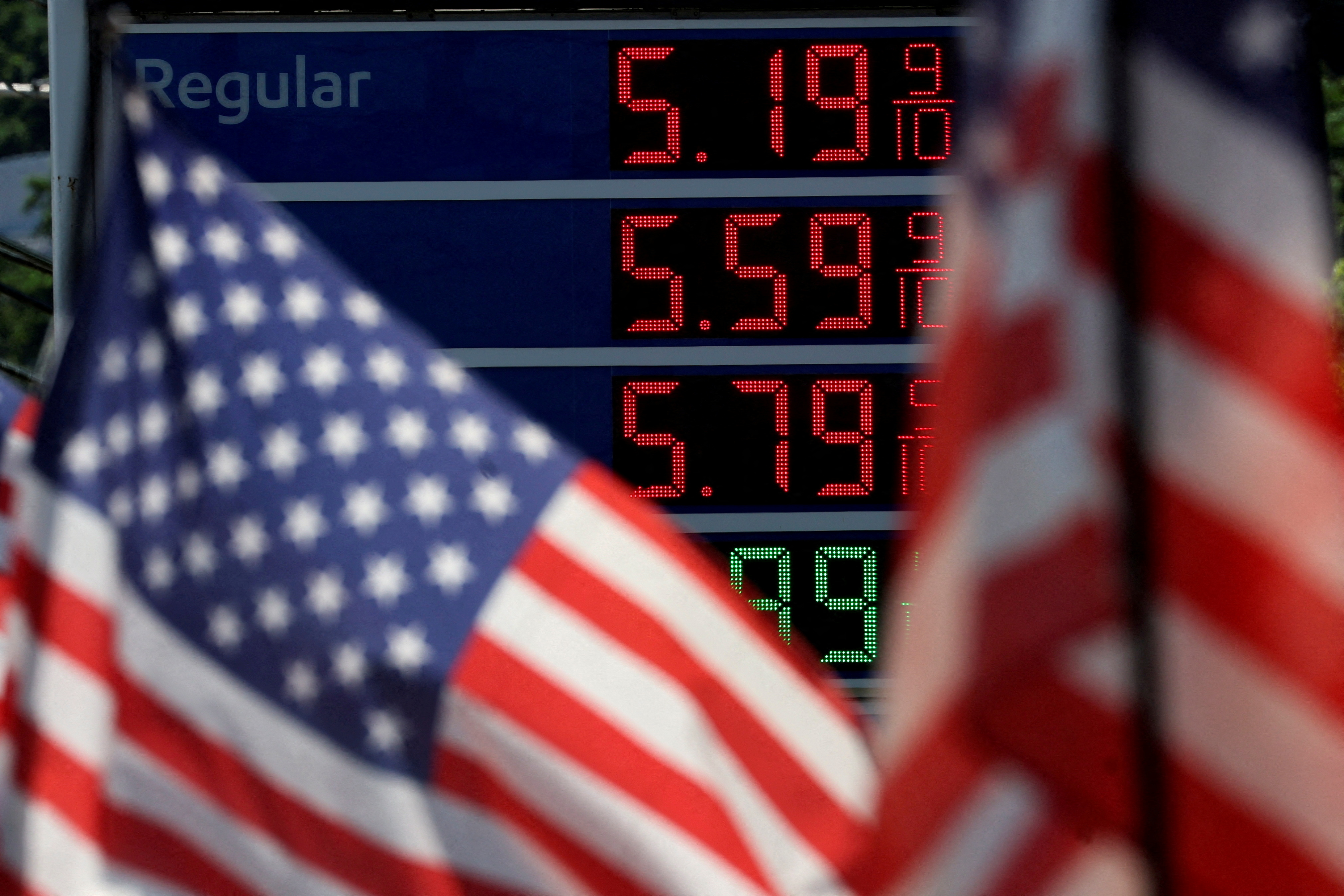 Gasoline prices are displayed at an Exxon gas station behind American flag in Edgewater, New Jersey, June 14, 2022.