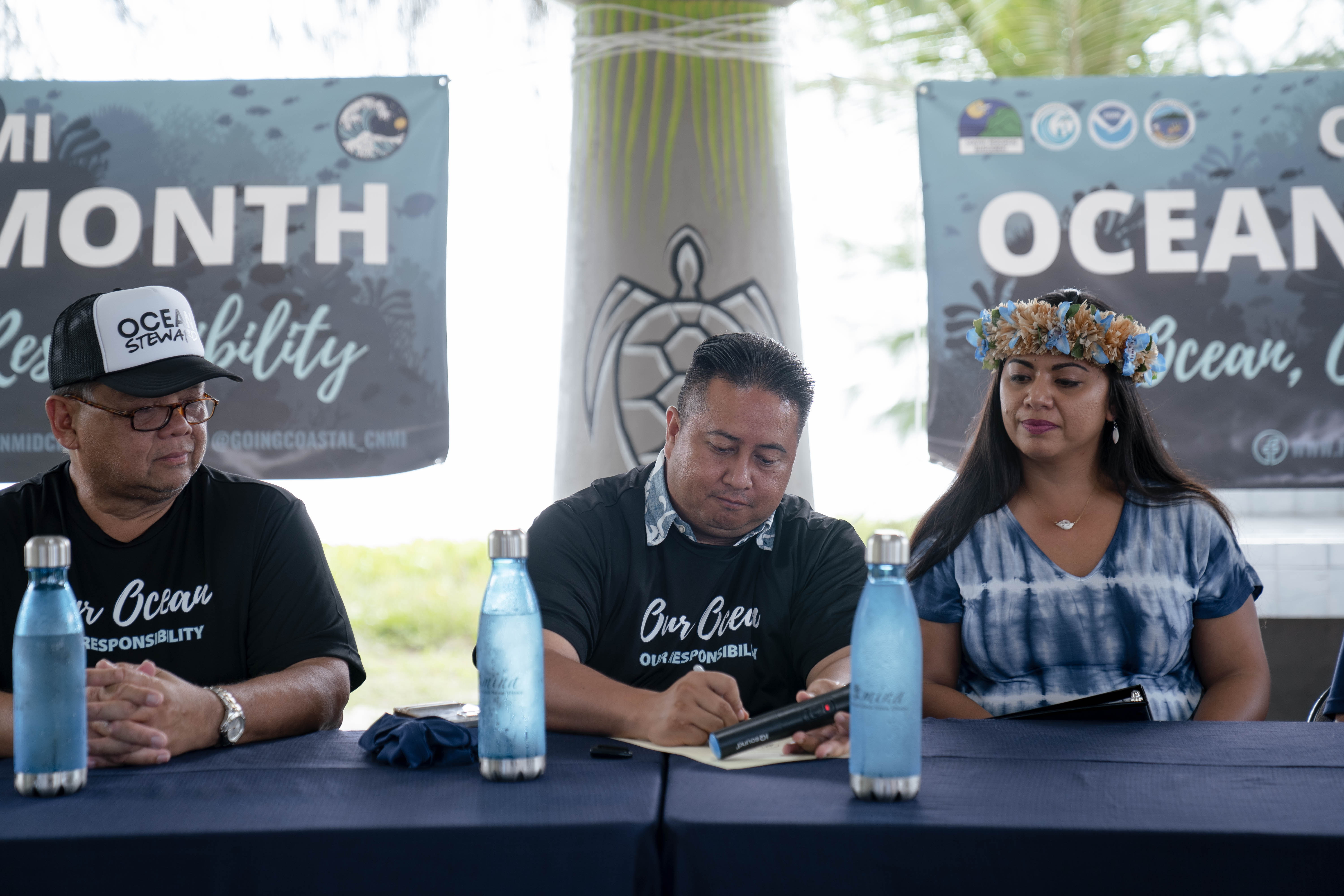 Bureau of Environmental and Coastal Quality Administrator Eli D. Cabrera, left, and Rep. Sheila J. Babauta, right, look on as Gov. Ralph DLG Torres signs a proclamation designating June as Ocean Month and June 8, 2022 as Ocean Day in the CNMI.