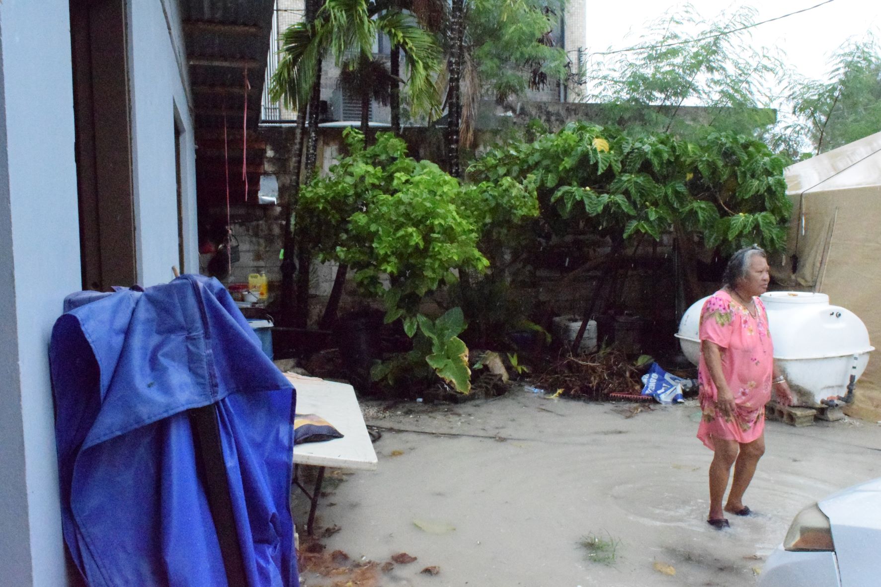 Quartermaster Road resident Rosa Rabauliman stands in her flooded yard following a downpour on Tuesday.