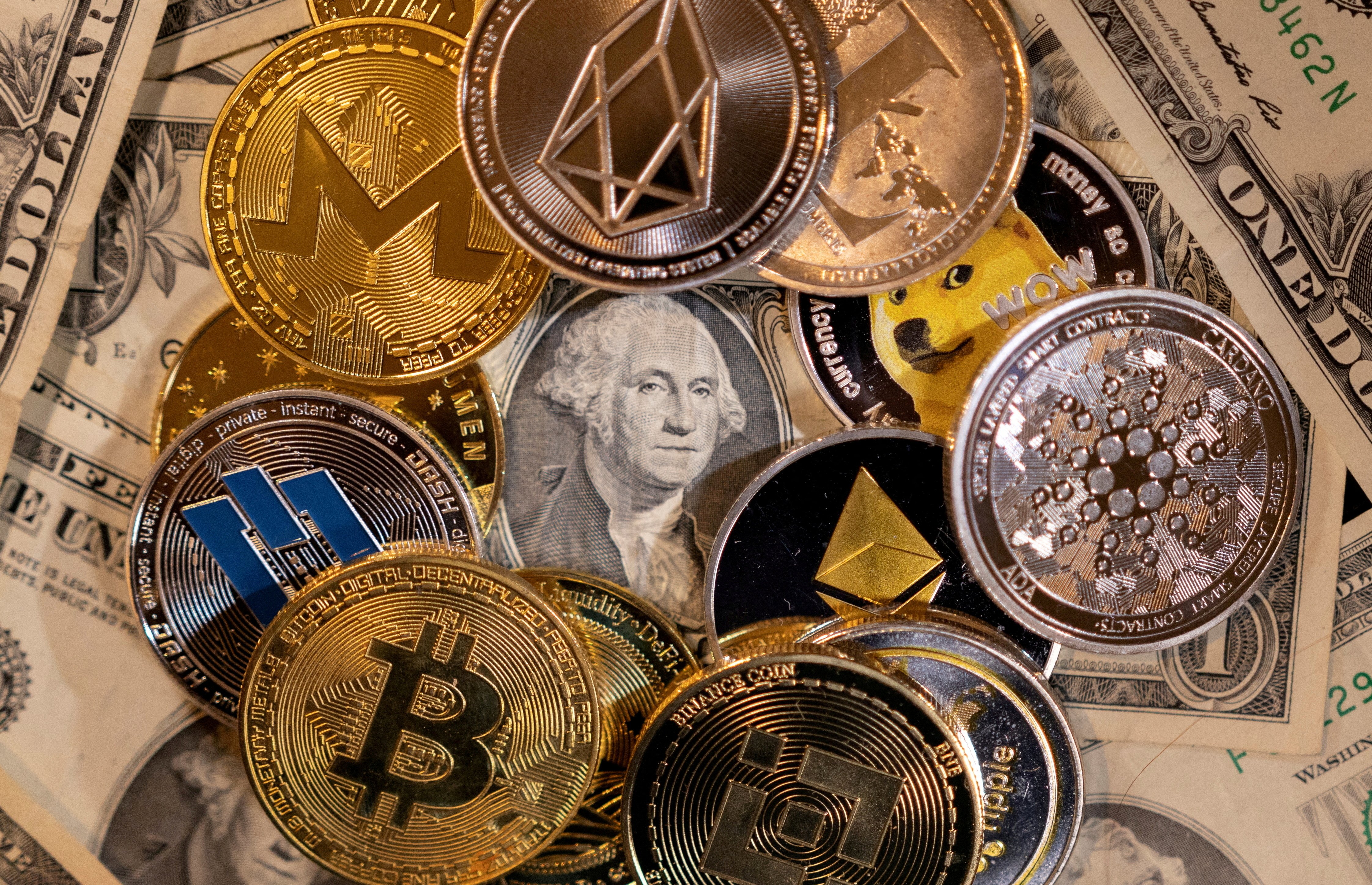 Representations of virtual cryptocurrencies are placed on U.S. dollar banknotes in this illustration taken on Nov. 28, 2021.