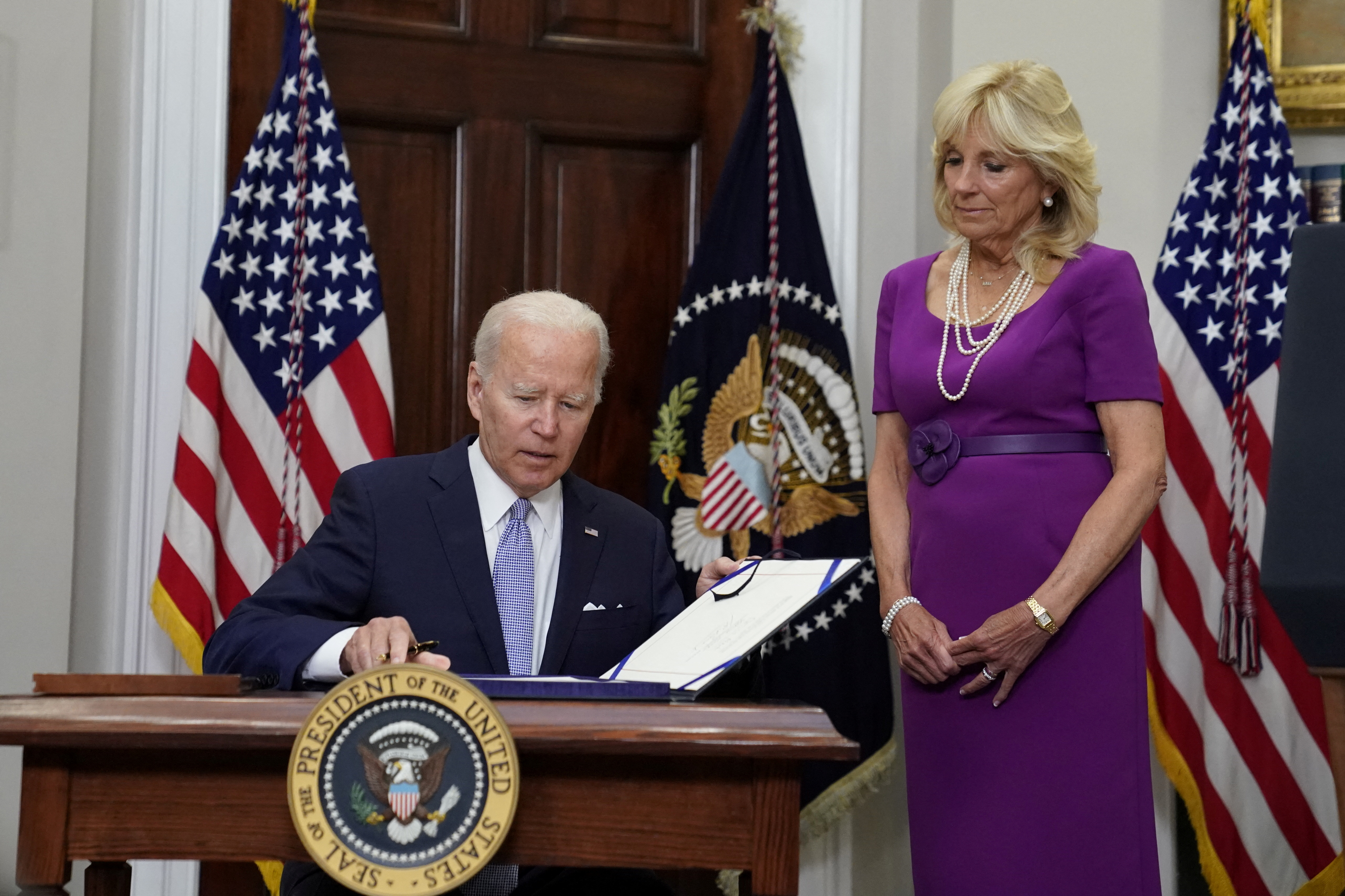 President Joe Biden signs S. 2938 or the Bipartisan Safer Communities Act into law from the Roosevelt Room at the White House as first lady Jill Biden stands next to him in Washington, D.C., June 25, 2022.