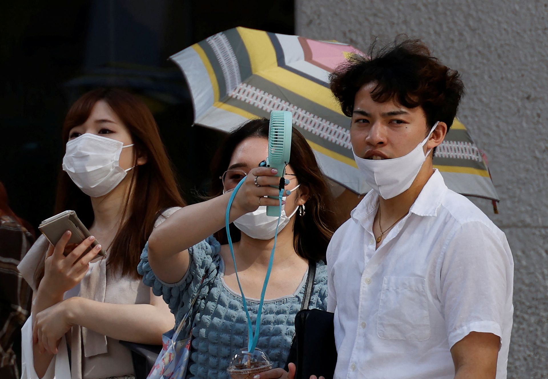 Pedestrians uses a portable fan on the street during a heatwave in Tokyo, Japan, June 27, 2022.