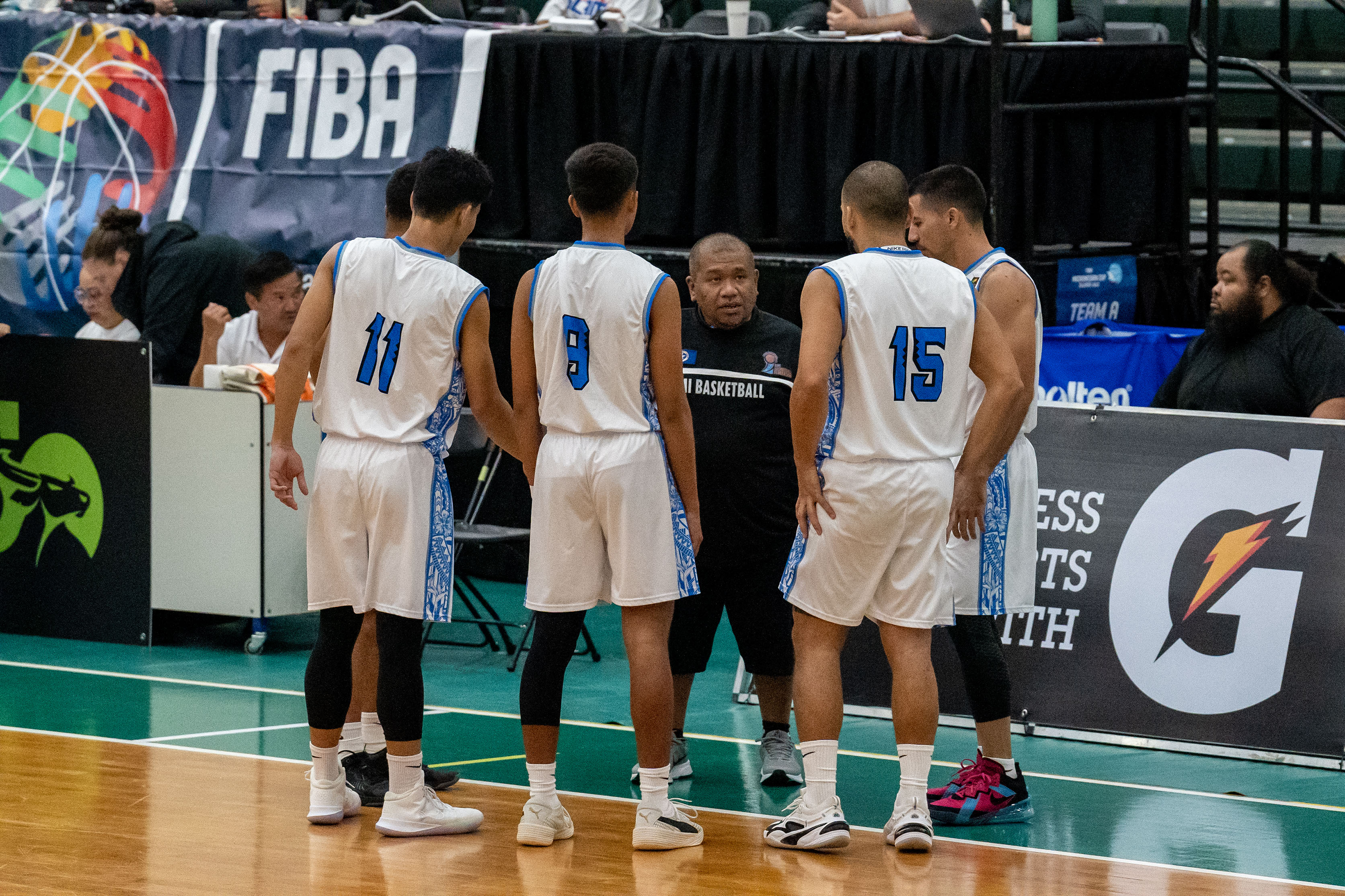 NMI Men's Coach Joe Diaz huddles with his players during a timeout.