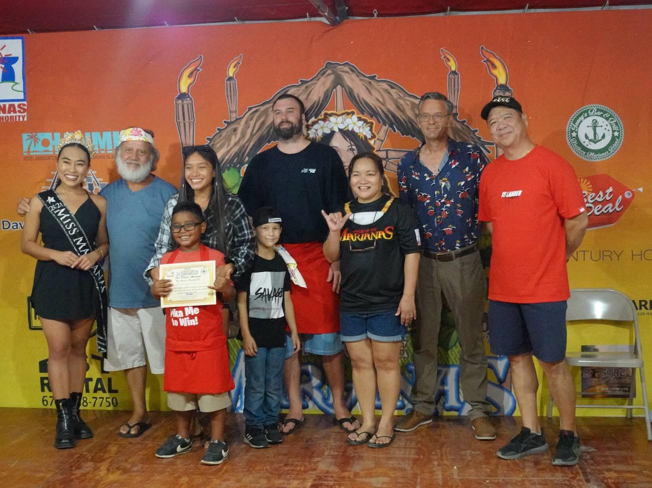 The Pika Me to Win duo of Donald Mendiola, send left, and Alex Standish, fourth right, win  1st   place  in the  Eskabeche  Cooking Contest  at  the  23rd  Annual  Taste  of  the Marianas International Food Festival & Beer Garden on June 19, 2022 at Garapan Fishing Base.   The team also won 1st  place in the Kadun Pika Cooking Contest the previous evening.