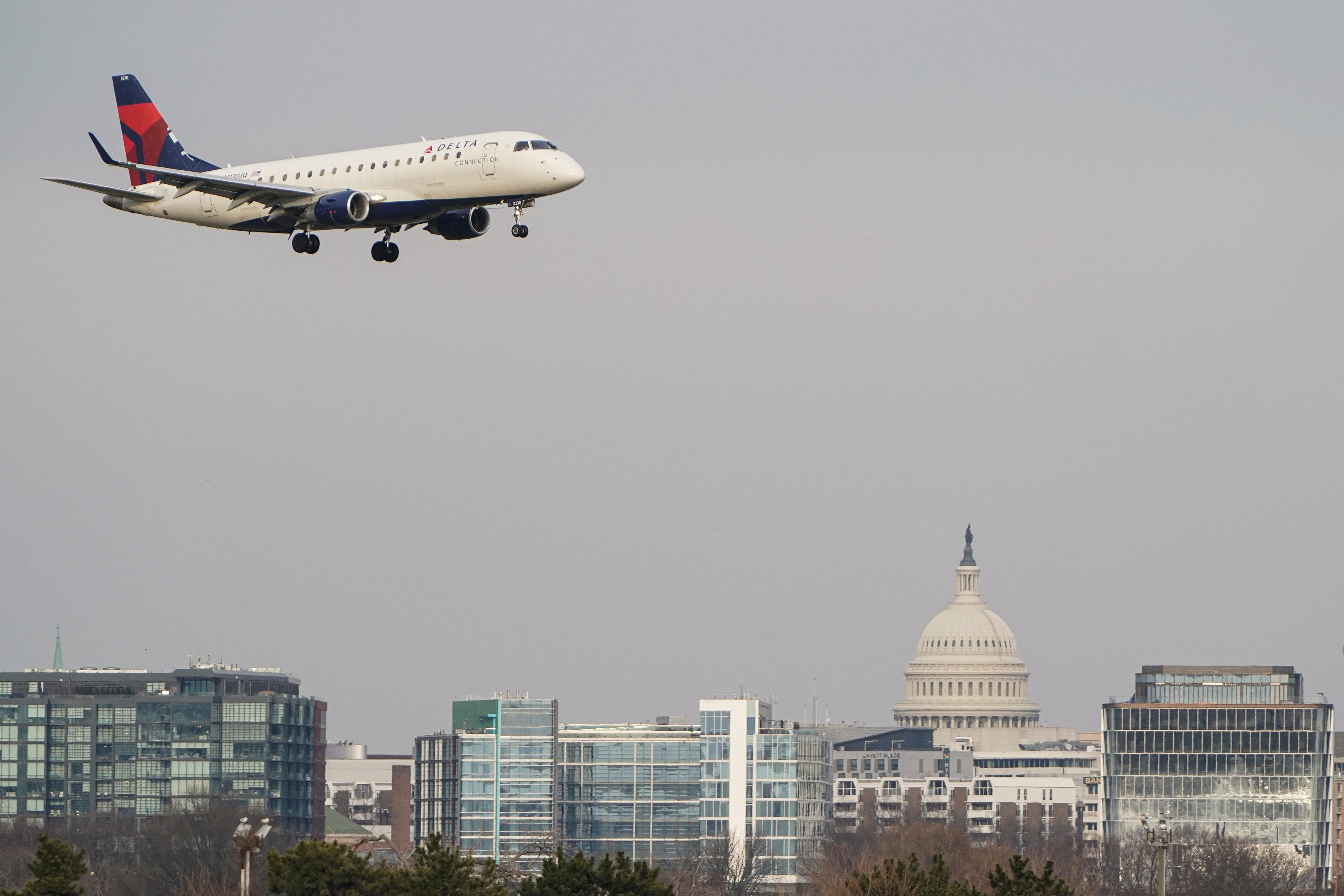 A Delta Air Lines aircraft flies past the U.S. Capitol before landing at Reagan National Airport in Arlington, Virginia, Jan. 24, 2022.