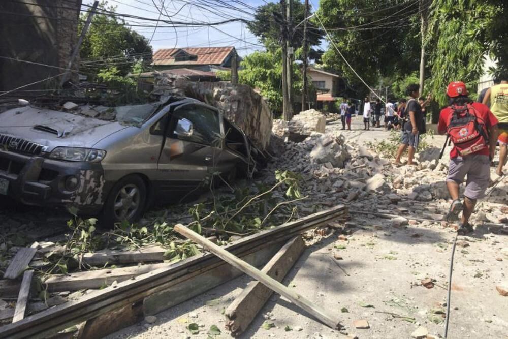 In this handout photo provided by the Philippine Red Cross, a vehicle is damaged as a wall collapses after a strong earthquake hit Ilocos Sur province, the northern Philippines on Wednesday, July 27, 2022.