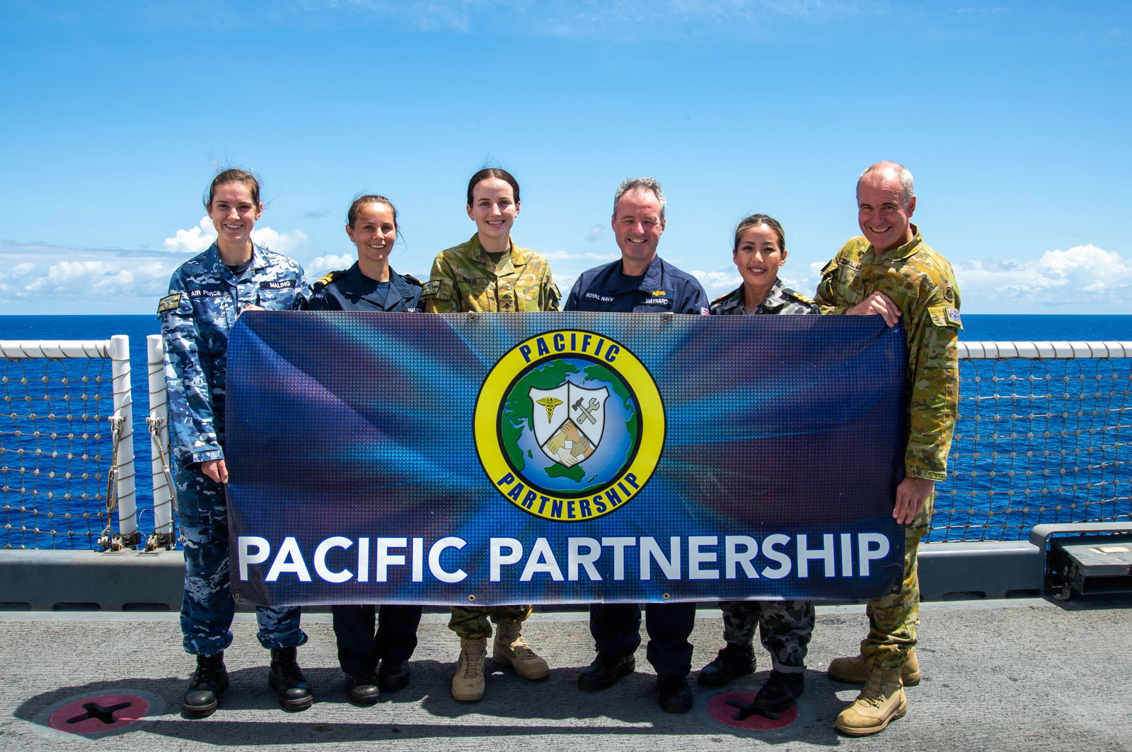 Royal Navy and Australian Defense Force personnel pose for a photo on the flight deck aboard Military Sealift Command hospital ship USNS Mercy (T-AH 19). Mercy is  part of Pacific Partnership 2022. Now in its 17th year, Pacific Partnership is the largest annual multinational humanitarian assistance and disaster relief preparedness mission conducted in the Indo-Pacific. 