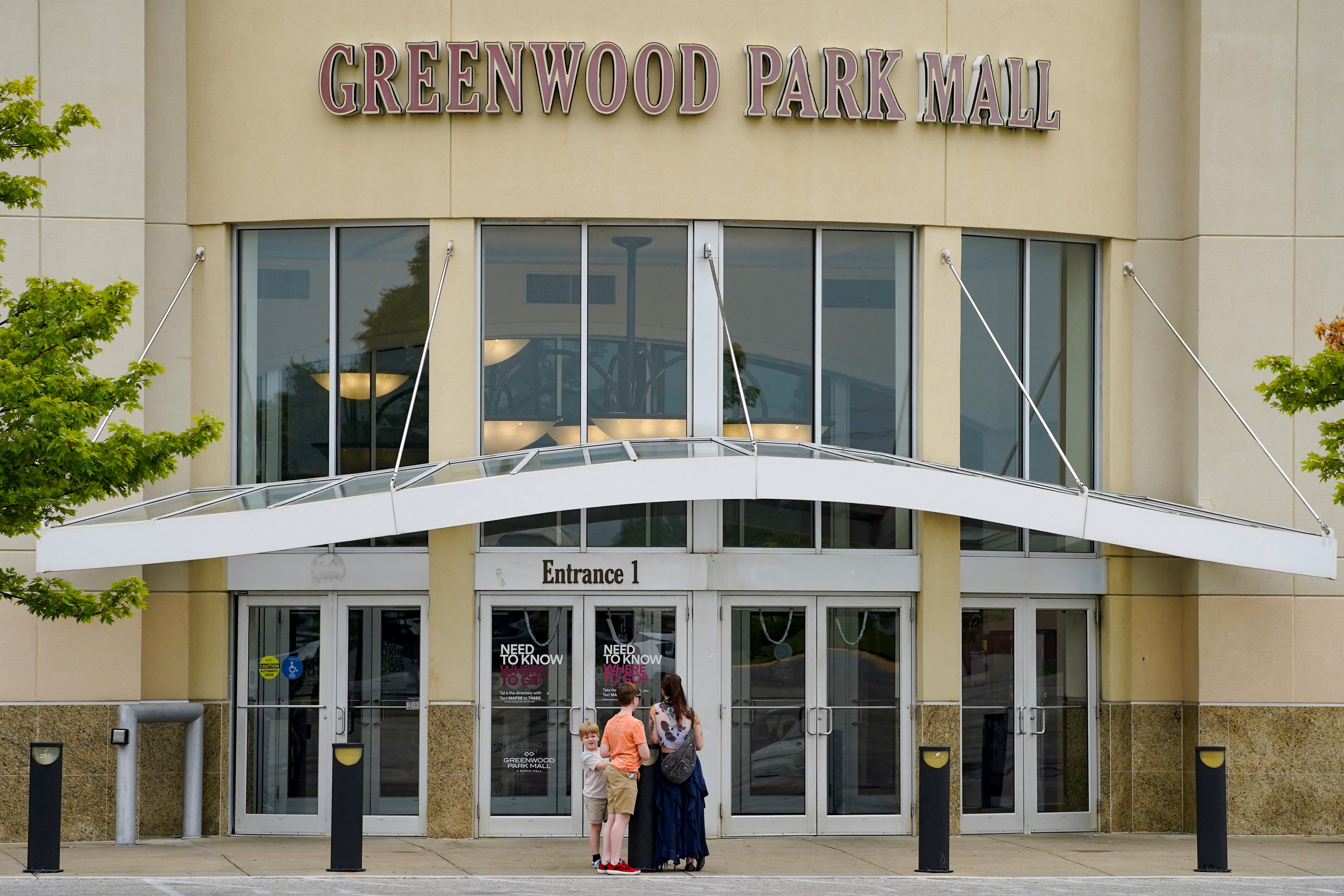 People stand at the entrance of Greenwood Park Mall the morning after a mass shooting in the Indianapolis suburb of Greenwood, Indiana, July 18, 2022.