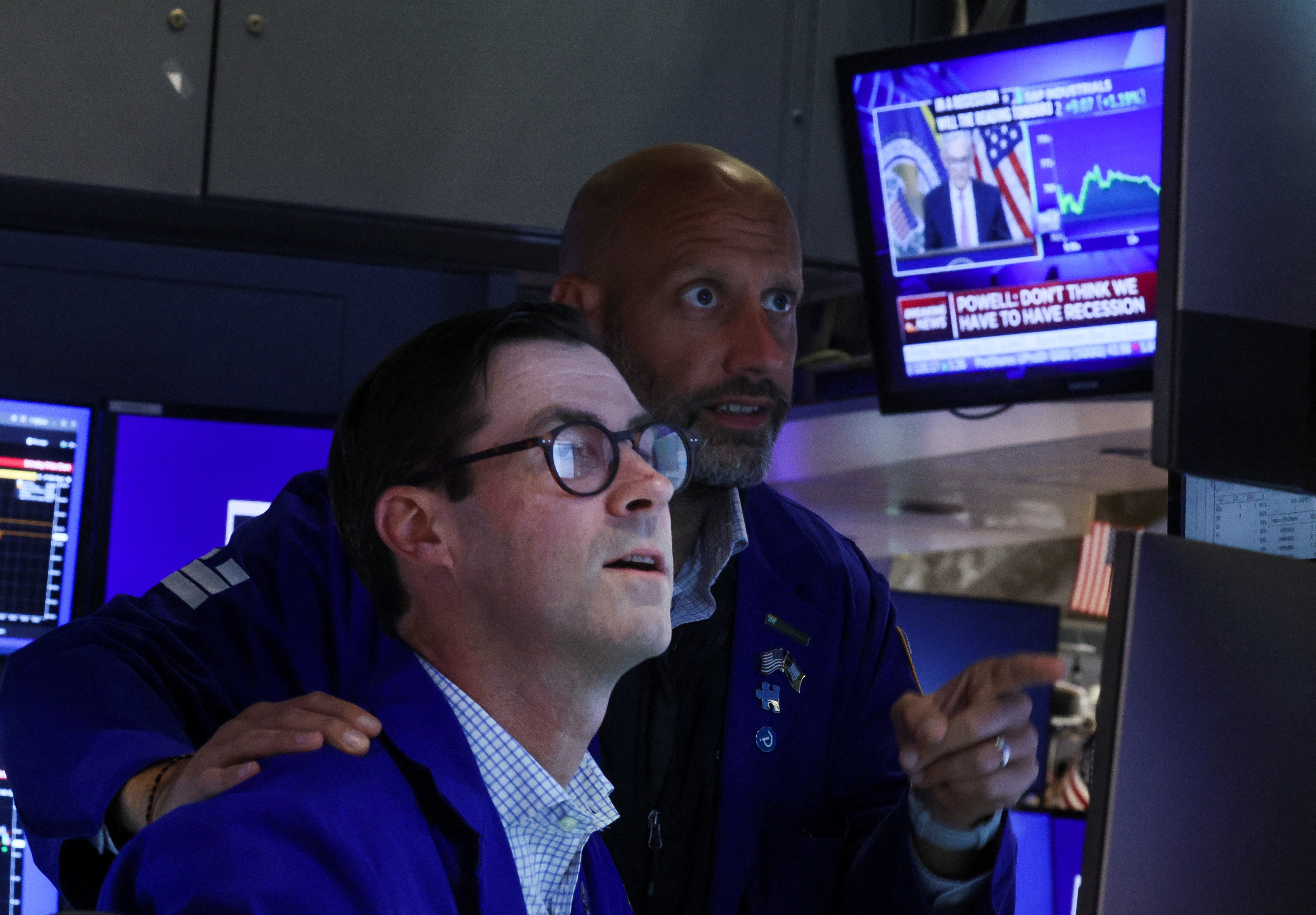 Traders react on the floor of the New York Stock Exchange as a screen shows Federal Reserve Board Chairman Jerome Powell during a news conference following a Fed rate announcement, in New York City, July 27, 2022.