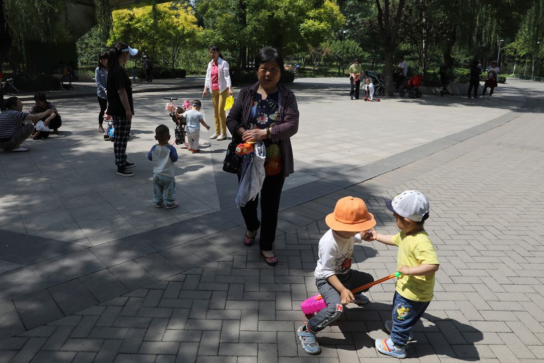 Children play next to adults at a park in Beijing, China on June 1, 2021.