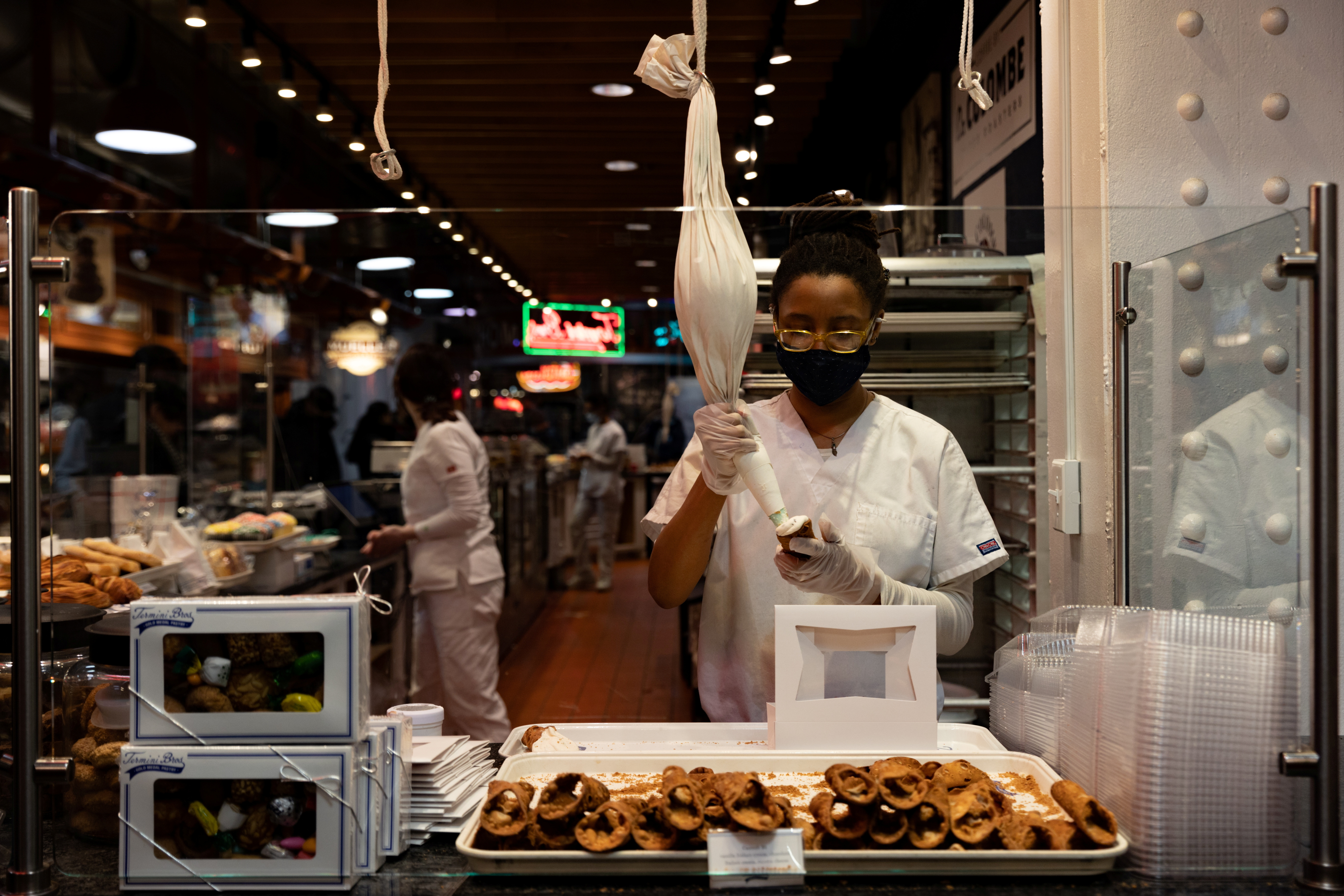 A worker fills a cannoli at a bakery at Reading Terminal Market in Philadelphia, Pennsylvania,  Feb. 19, 2022.