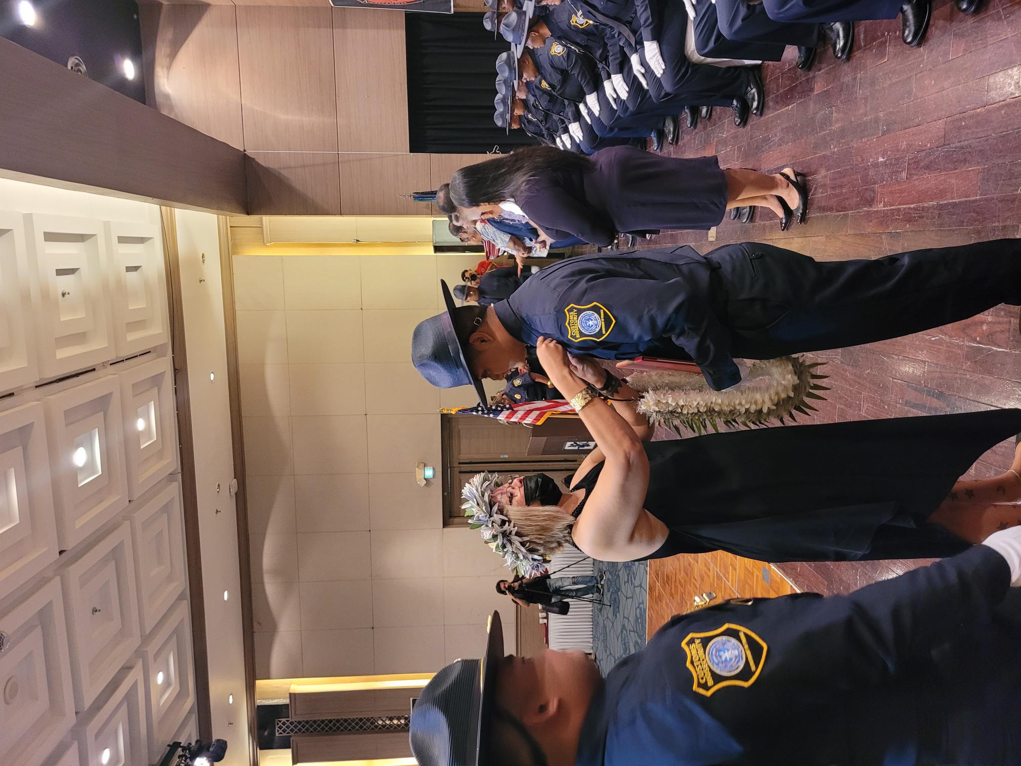 A family member pins a badge on Tindin Deleon Guerrero, the 9th Cycle Customs and Biosecurity Academy salutatorian.