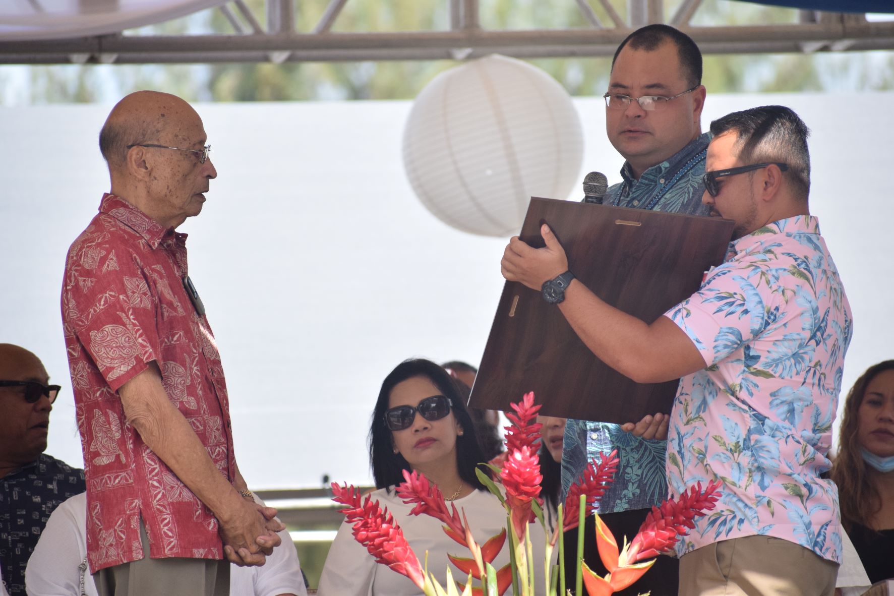 Speaker Edmund Sablan Villagomez is assisted by Rep. Joel Camacho as he reads House Resolution 22-21 to David "Uncle Dave" M. Sablan.