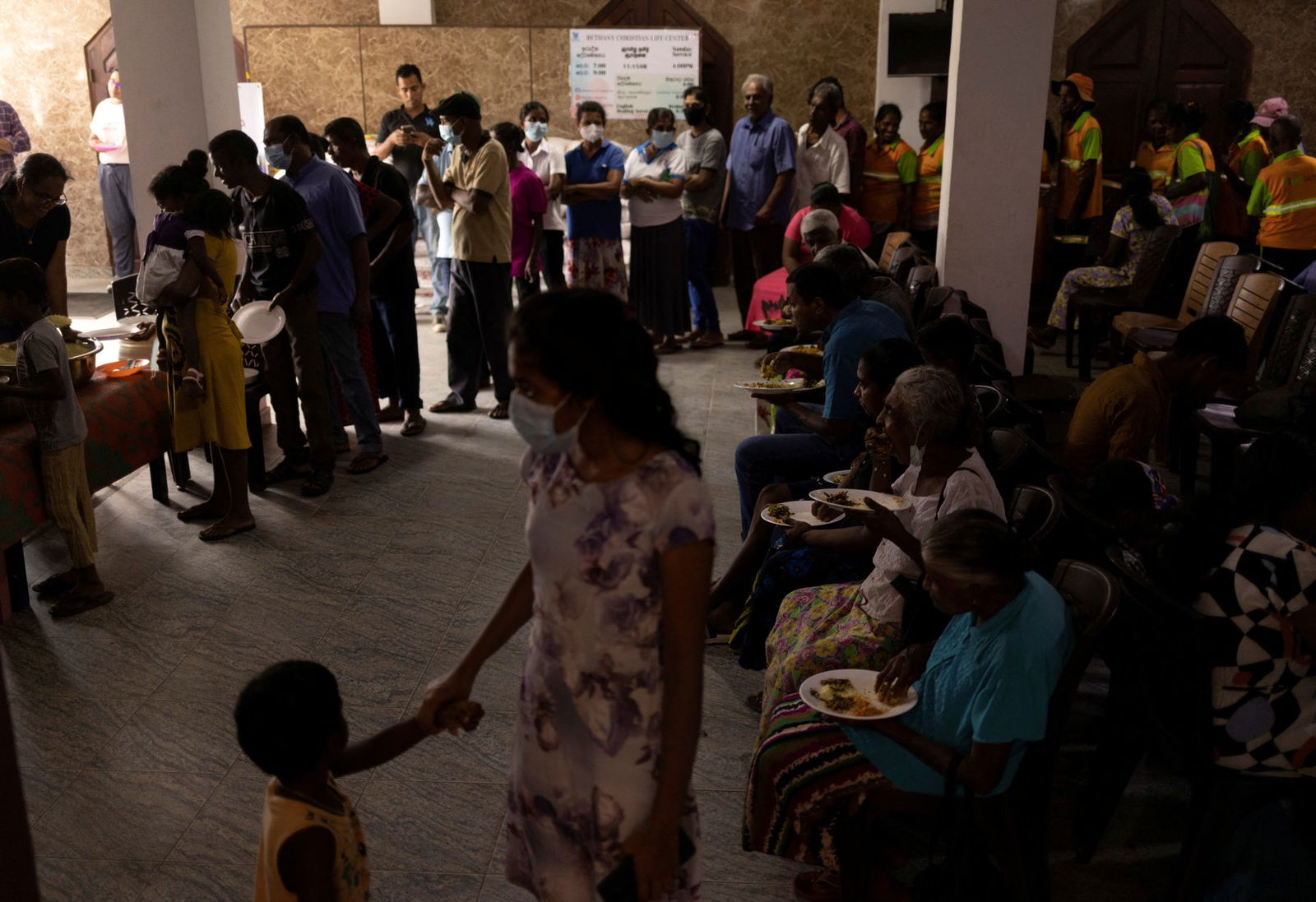 People eat at a community kitchen while others stand in a queue to receive food inside a church, amid the country's economic crisis, in Colombo, Sri Lanka, July 25, 2022.