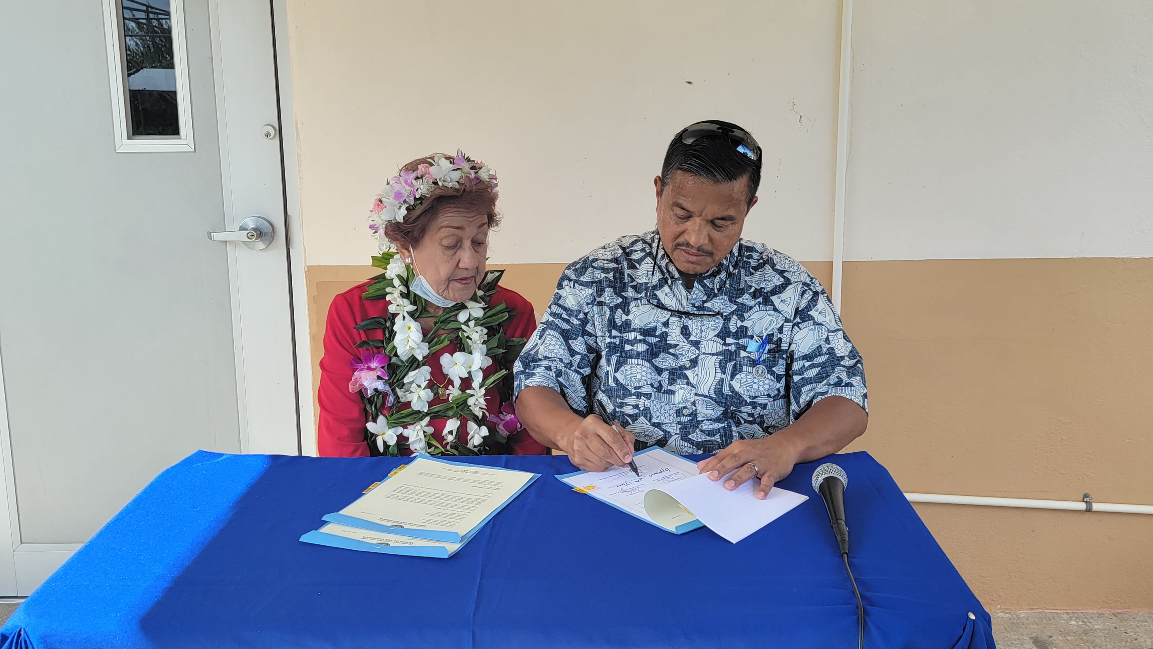 Retired educator Magdalena Muna Manglona Hofschneider, left, watches acting Gov. Jude U. Hofschneider sign Senate Bill 22-59 into Public Law 22-20 at the Head Start center in San Jose, Tinian on Thursday.