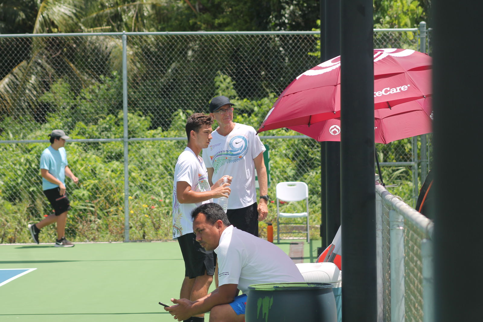 Robbie Schorr with NMI tennis coach Jeff Race during a break from a 2022 Pacific Mini Games tennis match at an American Memorial Park tennis court last week.