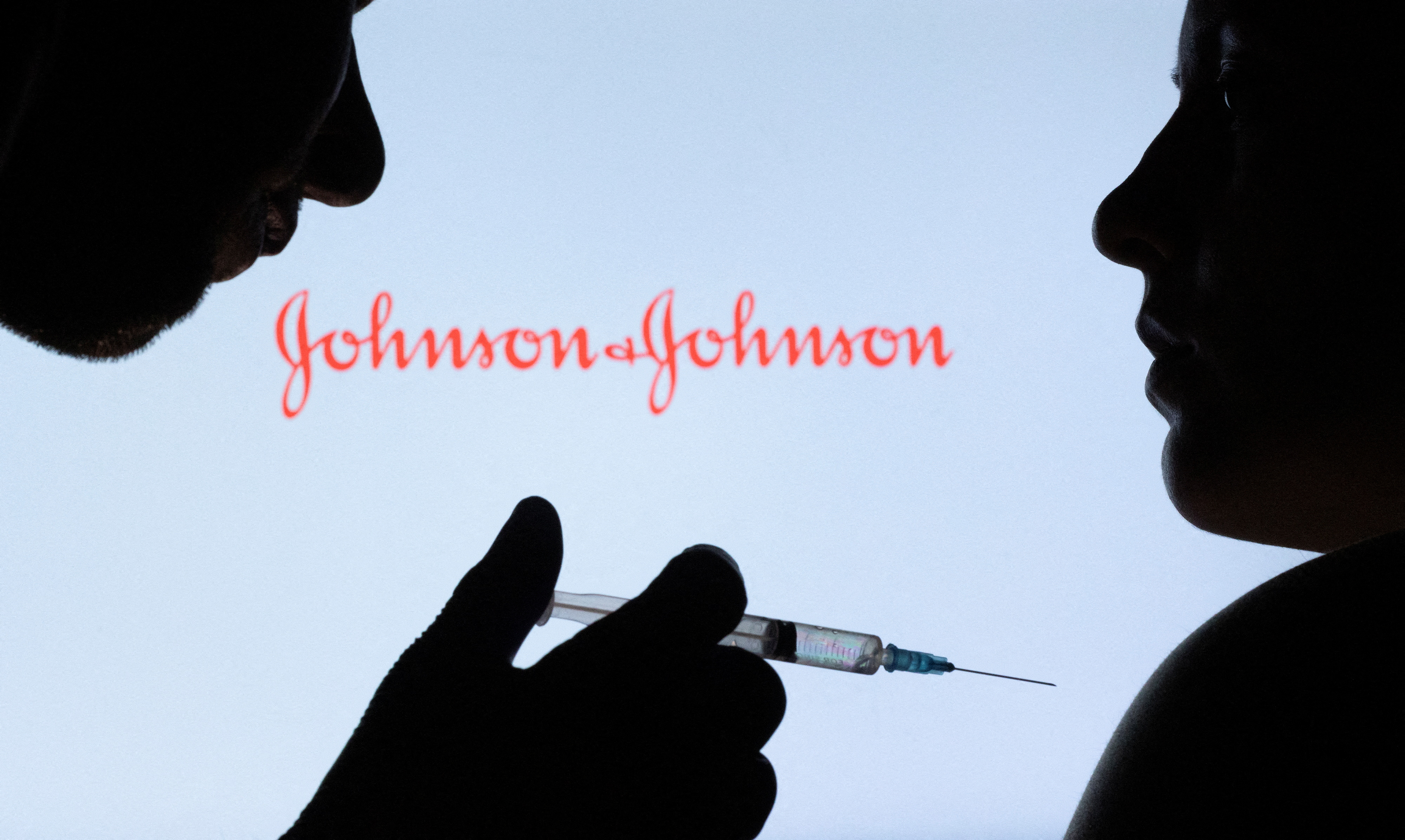 People pose with syringe with needle in front of a displayed Johnson & Johnson logo in this illustration taken Dec. 11, 2021.