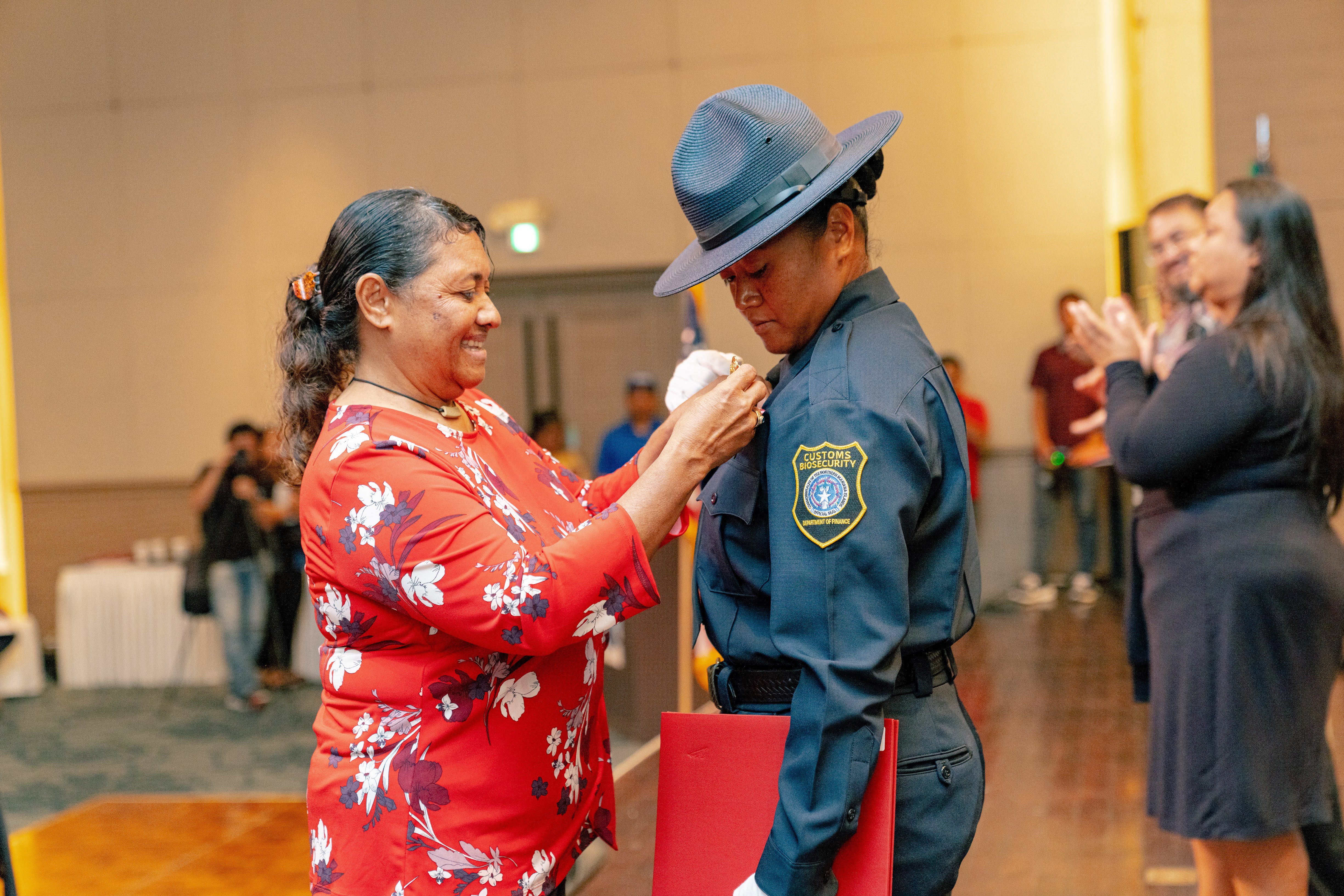 9th Cycle Academy graduate and class valedictorian Uchelbil E. Oiterong receives her badge from her mother.