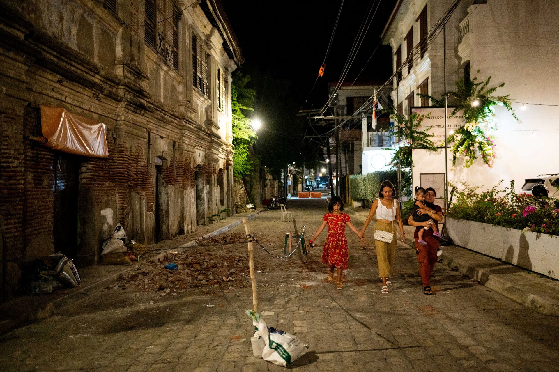 People walk past debris from a damaged building following an earthquake in Vigan City, Ilocos Sur, in the northern Philippines, July 27, 2022.